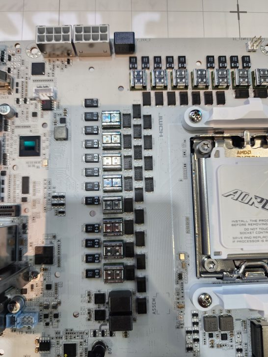 A close-up of an AMD motherboard featuring the socket area with 'AMP' text visible, surrounded by a series of capacitors and power connectors.