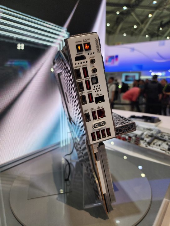 The back panel of an Aorus motherboard featuring multiple USB ports, HDMI, DisplayPort, and audio jacks displayed at a tech event.