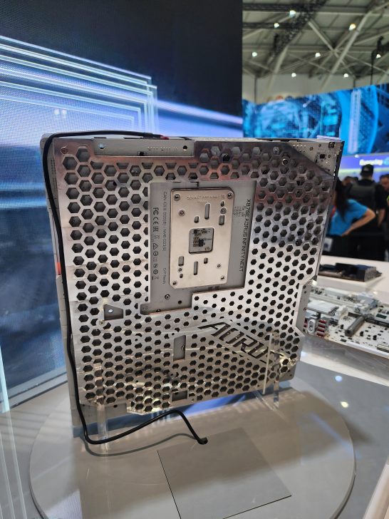 The back of an AORUS motherboard display with a hexagonal perforated design, showing a labeled 'Socket AM5' and various ports at a technology exhibition.