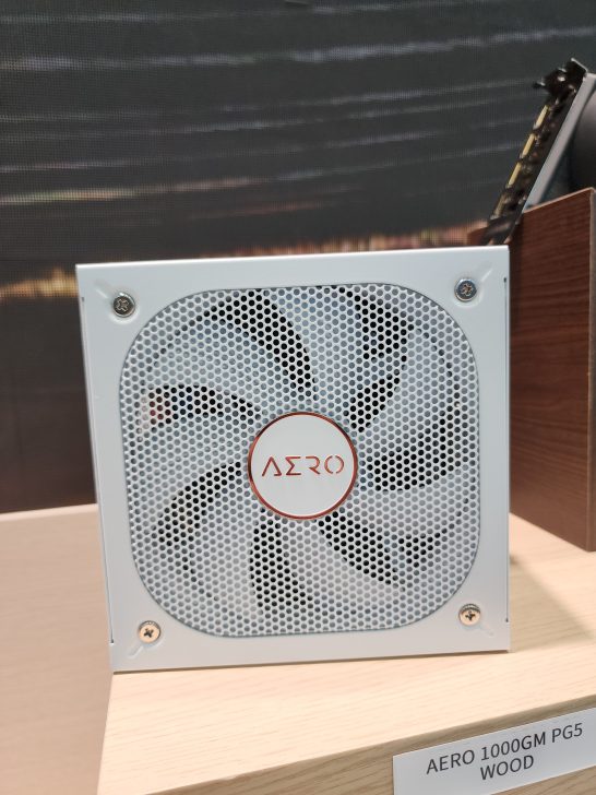 A white AERO 1000GM PG5 power supply with a fan is displayed on a light wood surface.