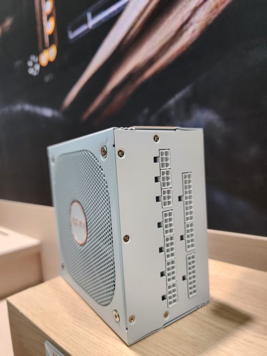 A close-up of an unbranded white power supply unit with multiple modular ports displayed on a wooden surface.