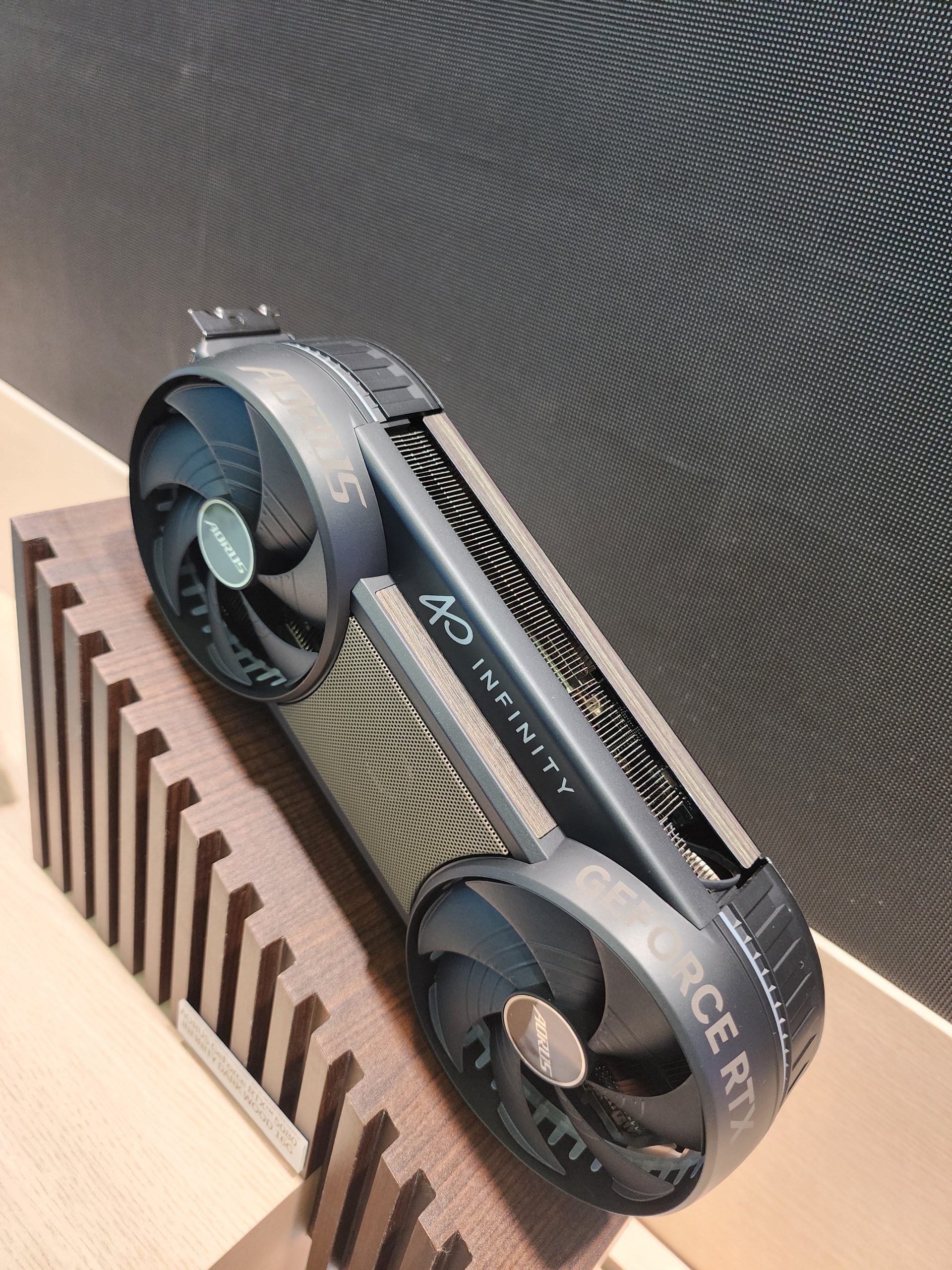 A custom-designed ASUS graphics card marked with 'AORUS' and 'GEFORCE RTX' featuring two large fans on a display stand.