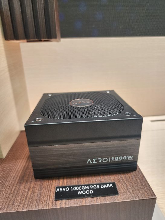 A computer power supply labeled Aero 1000GM 1000W rests on a display with a plaque reading 'AERO 1000GM PG5 DARK WOOD'.