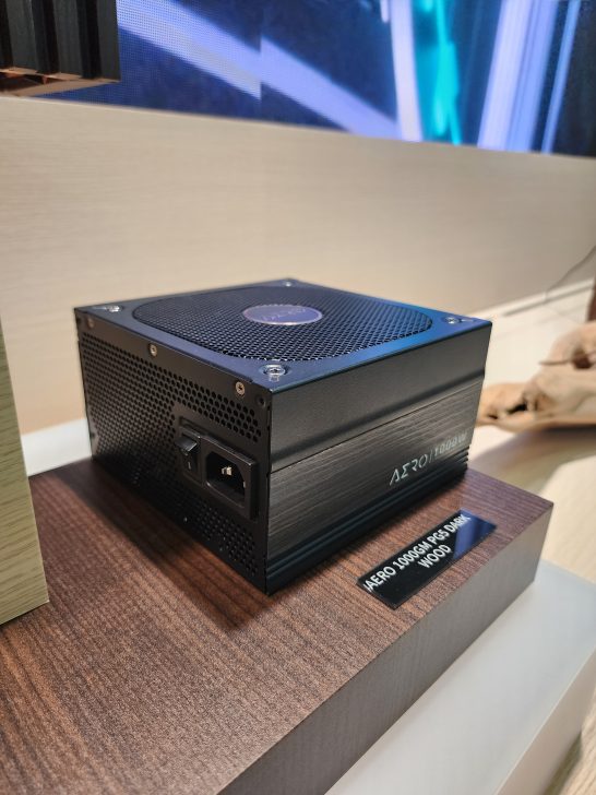 AERO 1000W power supply displayed on a wooden platform labeled 'AERO 1000GM PG5 DARK WOOD.'
