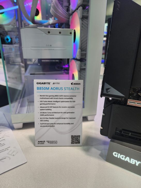 A Gigabyte B850M Aorus Stealth gaming PC with RGB fans and a sign listing its features, including 'X3D Turbo Mode' and M.2 EZ-Freeze cooling.