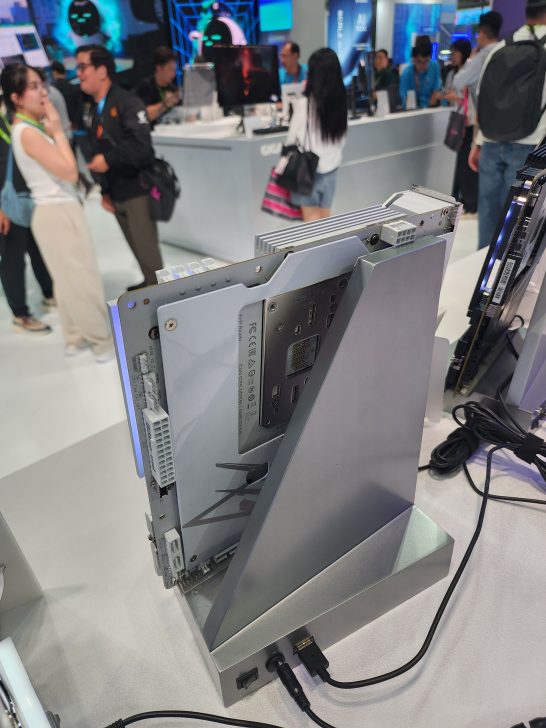 A vertically mounted EZDIY-FAB PCIe riser is displayed on a stand at a technology exhibition booth.