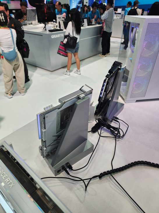 Two NVIDIA GeForce RTX graphics cards are displayed vertically on stands at a Gigabyte booth during an electronics exhibition.
