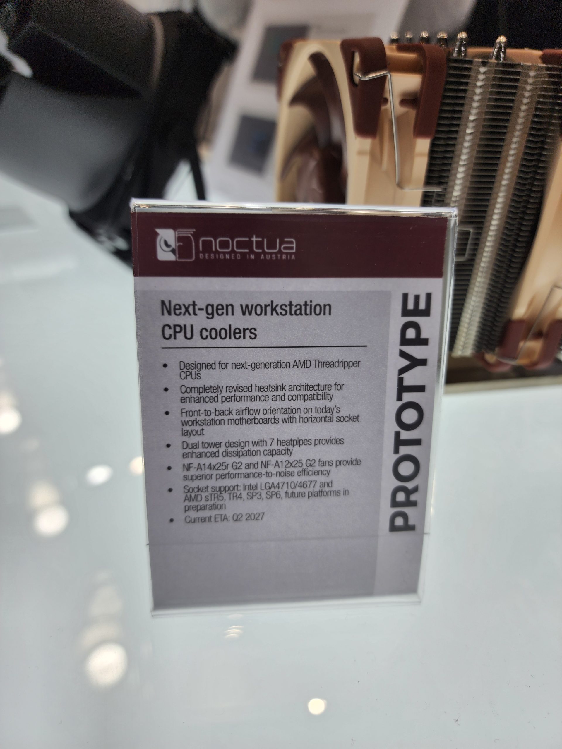 A Noctua prototype next-gen workstation CPU cooler is displayed alongside a sign highlighting features like its dual tower design with seven heatpipes and compatibility with Intel LGA4710/4767 and AMD sTR5 sockets, with an ETA of Q2 2027.
