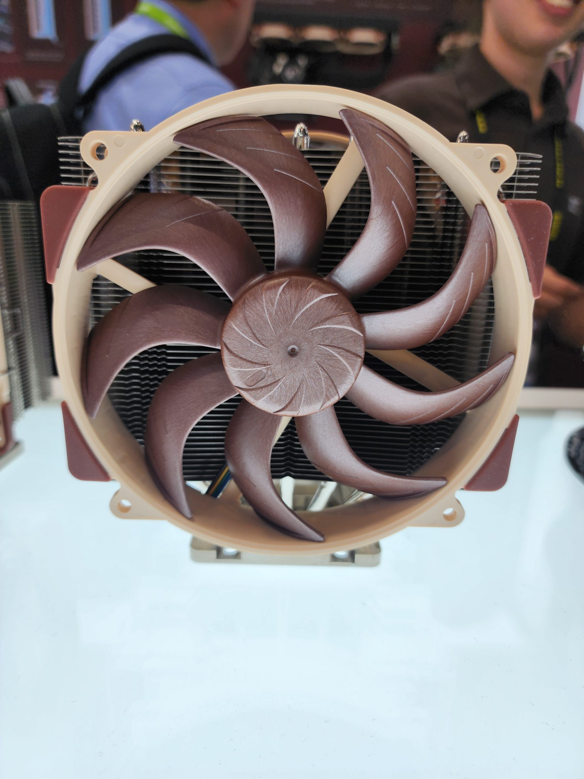 A Noctua CPU cooler featuring a large brown and beige fan on display at a tech event.