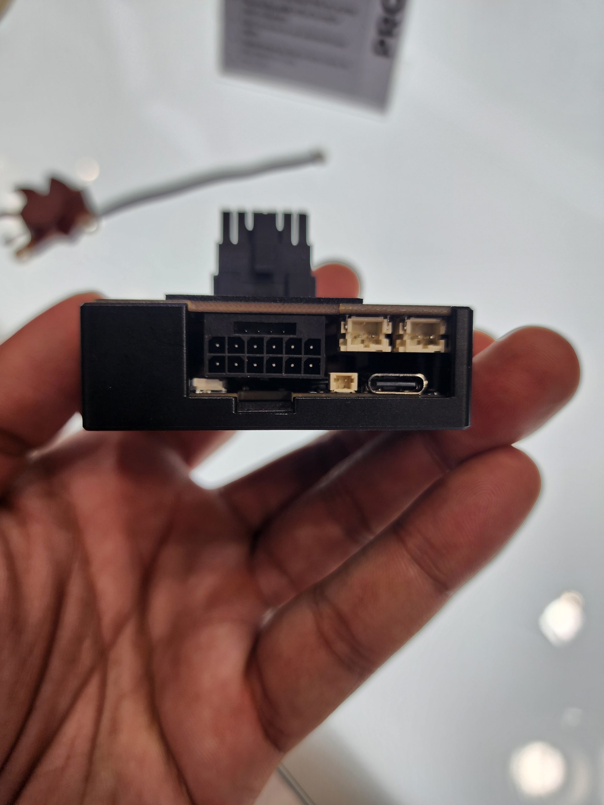 A hand holding a PCIe adapter with visible connectors including an 8-pin, two 4-pin, and a USB Type-C port.