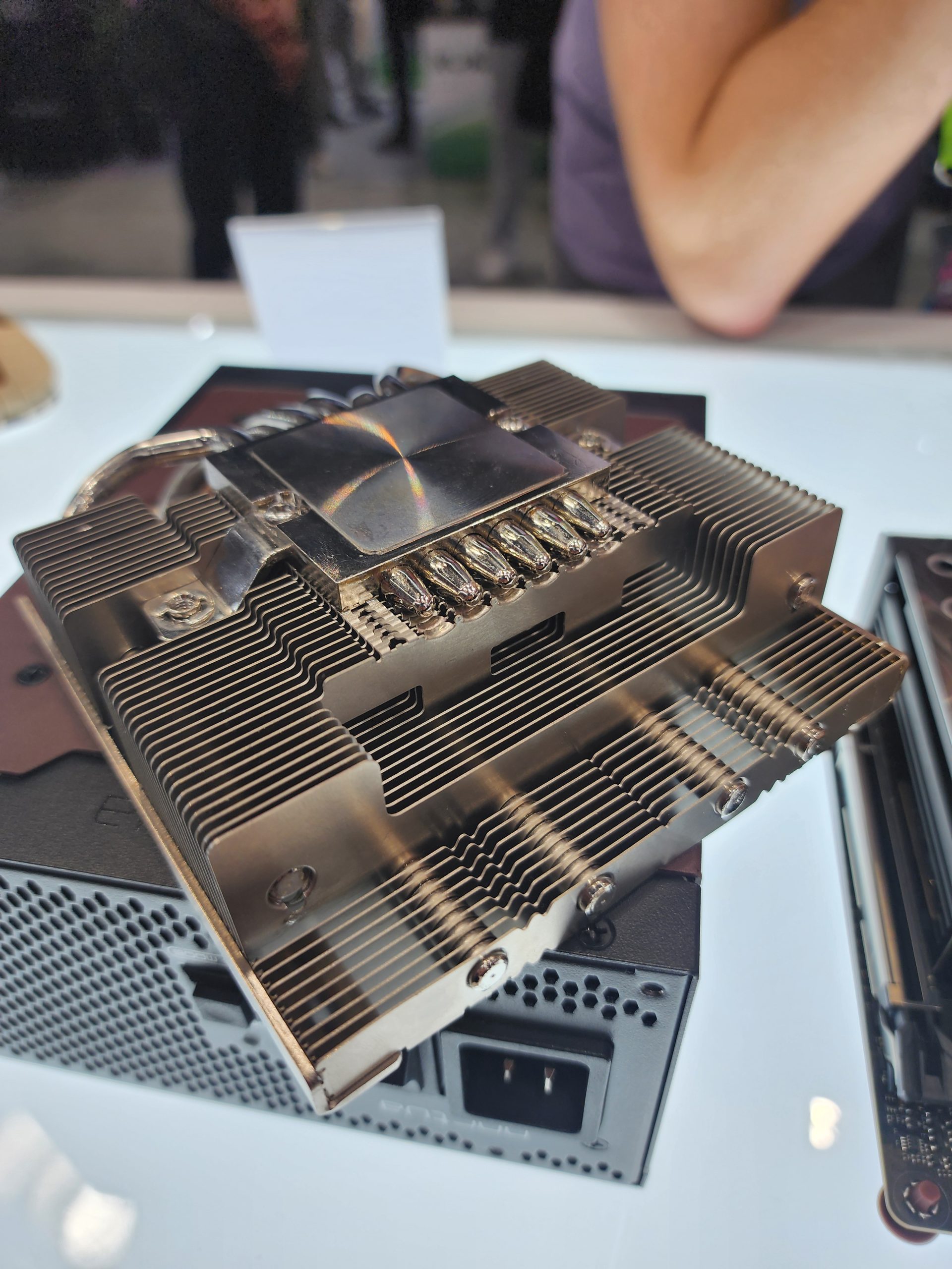 A close-up of a metal heatsink with multiple heat pipes on display at an electronics event.