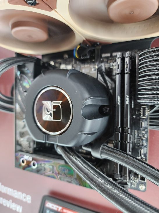 A close-up of an ASUS ROG motherboard with a Cooler Master liquid cooler and two Kingston Fury RAM modules installed.