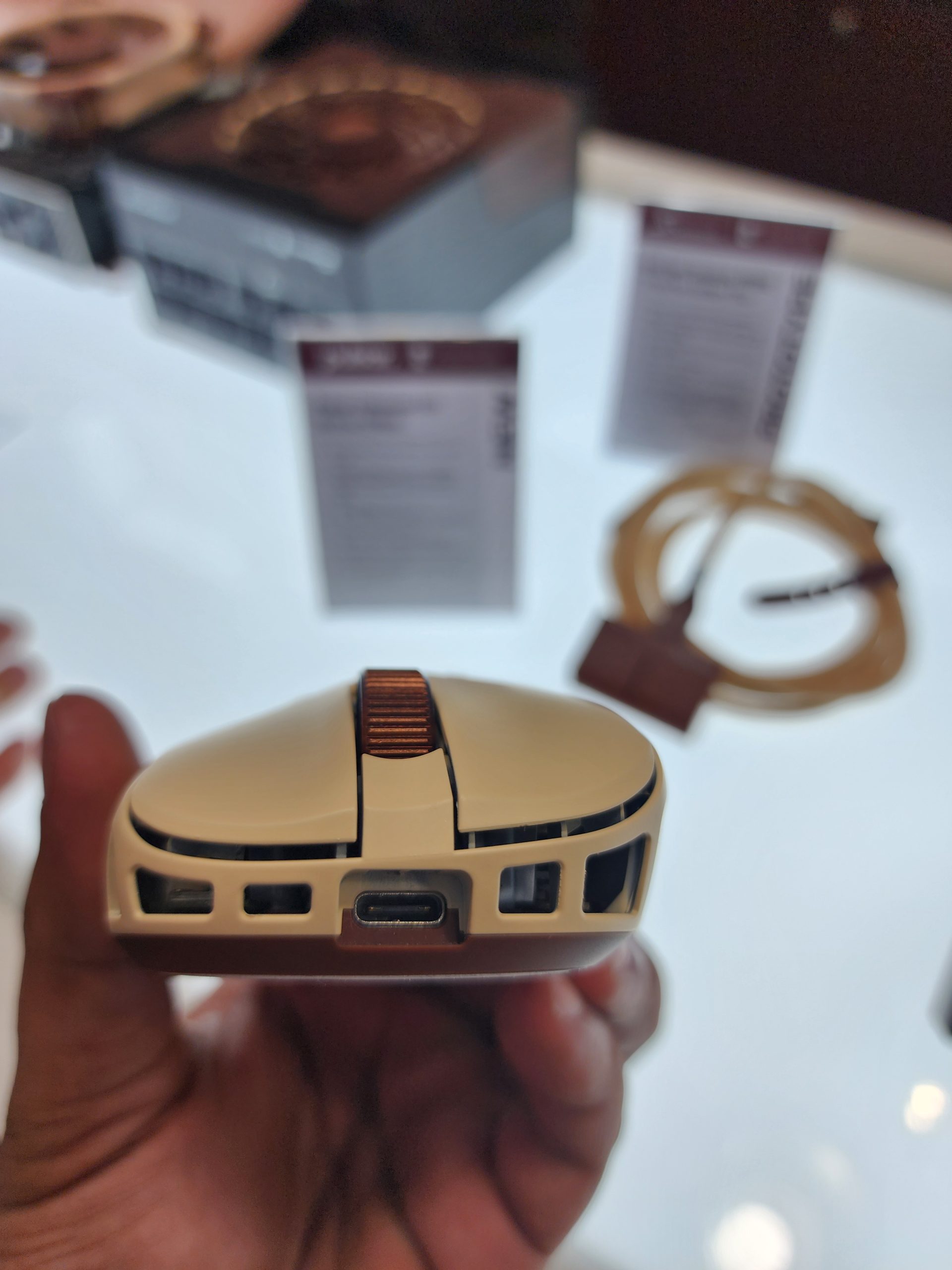 A close-up view of a Noctua Edition gaming mouse with a detailed look at its frontside design, USB-C port, and a scroll wheel colored in the brand's signature brown.