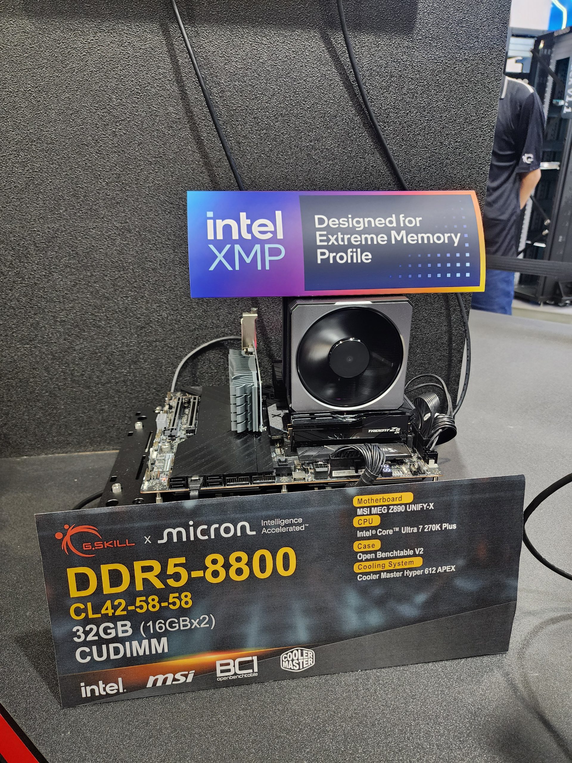 A hardware setup featuring a G.SKILL x Micron DDR5-8800 memory module on an MSI MEG Z690 UNIFY-X motherboard with an Intel Core i7 Ultra 7 270K Plus CPU, accompanied by a Cooler Master Hyper 612 APEX cooling system, with signage promoting 'intel XMP' Designed for Extreme Memory Profile.