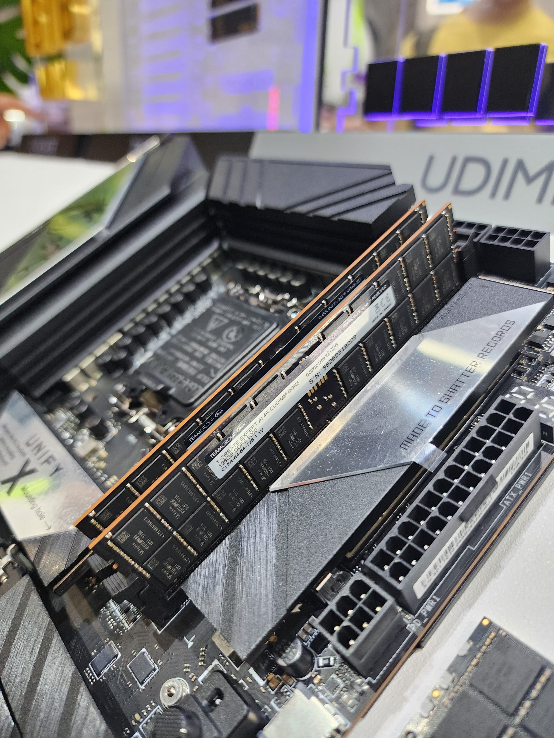 A close-up of TeamGroup DDR5 memory modules installed on a motherboard labeled 'UDIMM' with surrounding electronic components.