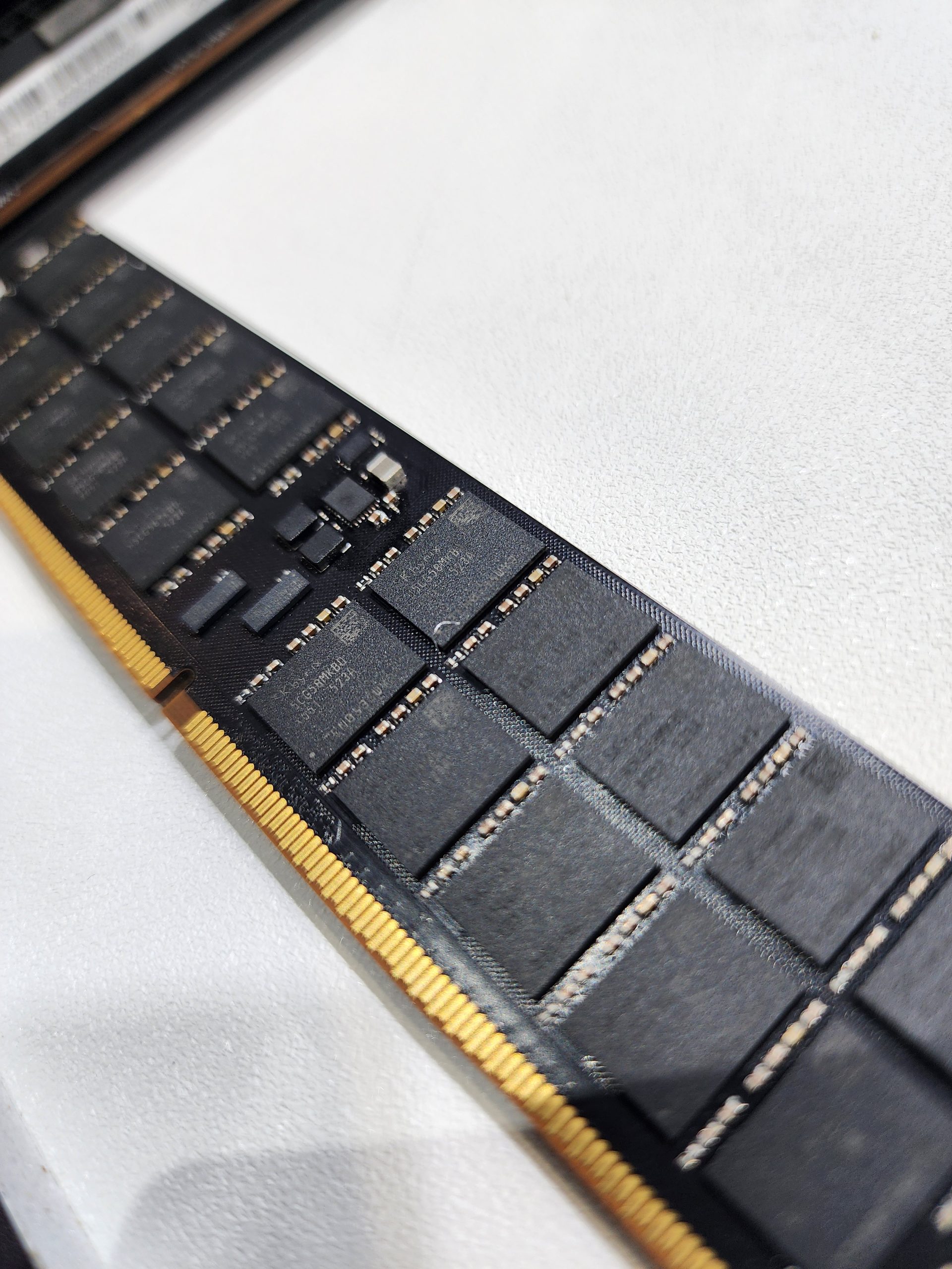 A detailed view of unbranded DDR5 RAM modules on a white surface, featuring close-up details of the chips and golden connectors.