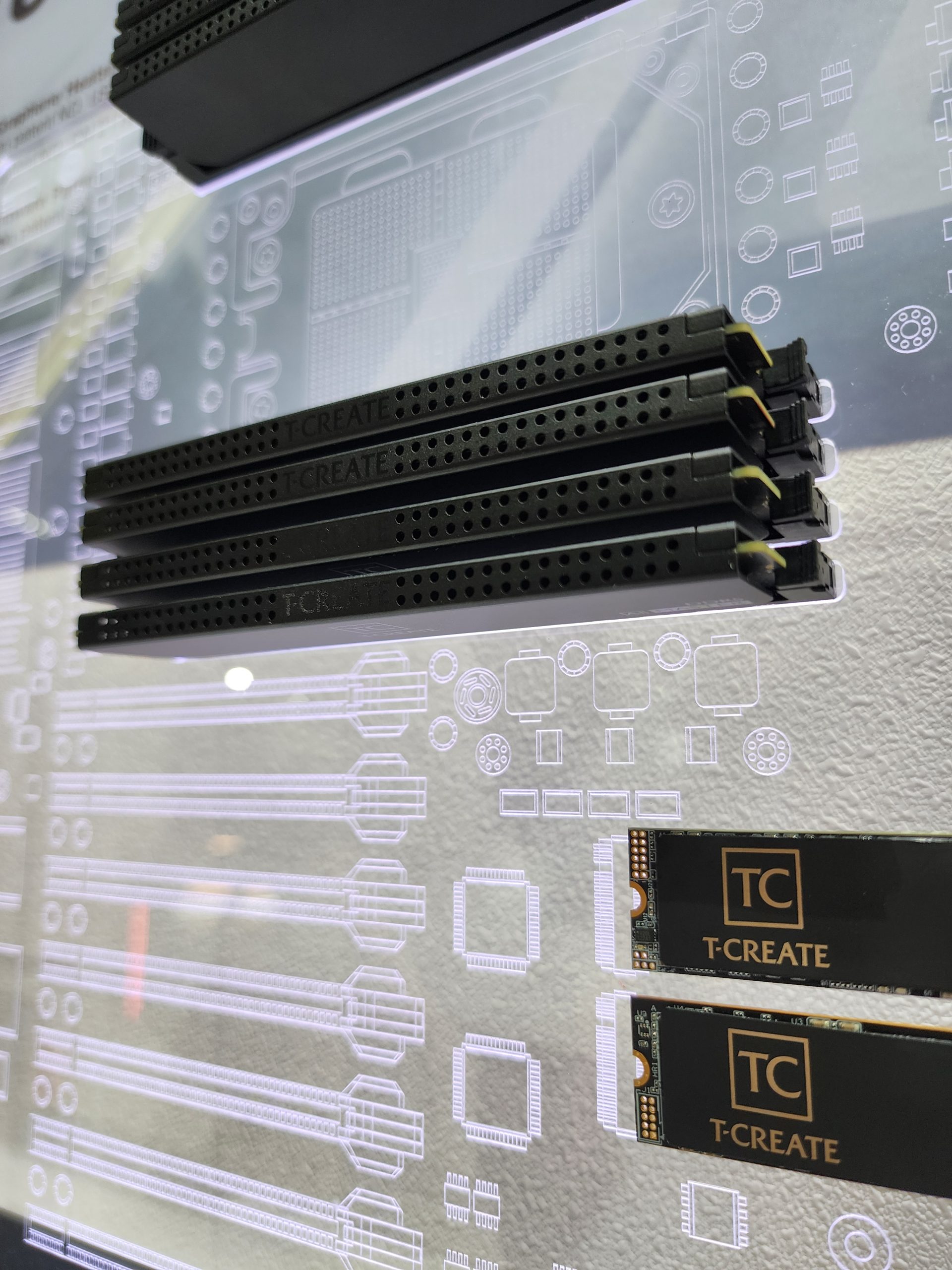 T-CREATE branded memory modules and SSDs are displayed against a circuit board blueprint backdrop.