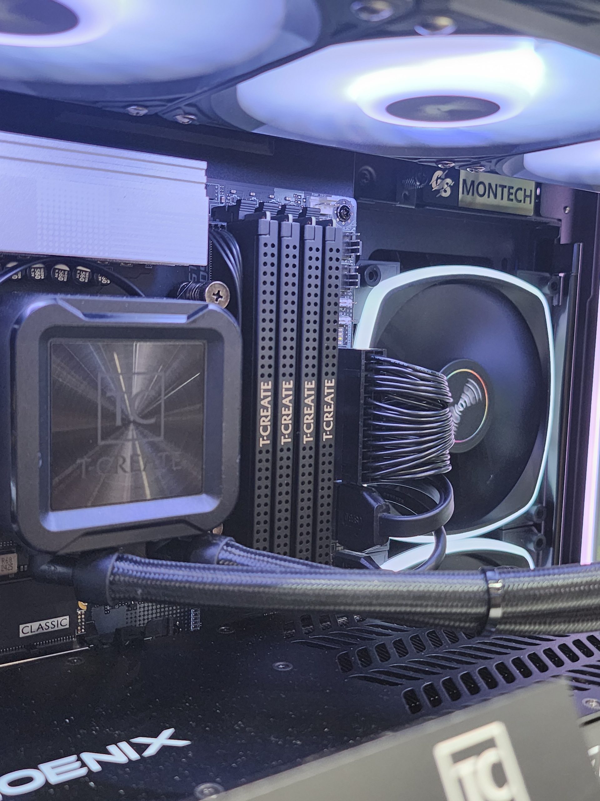 A desktop PC build with T-CREATE RAM modules, a Montech fan, and a graphics card labeled PHOENIX.
