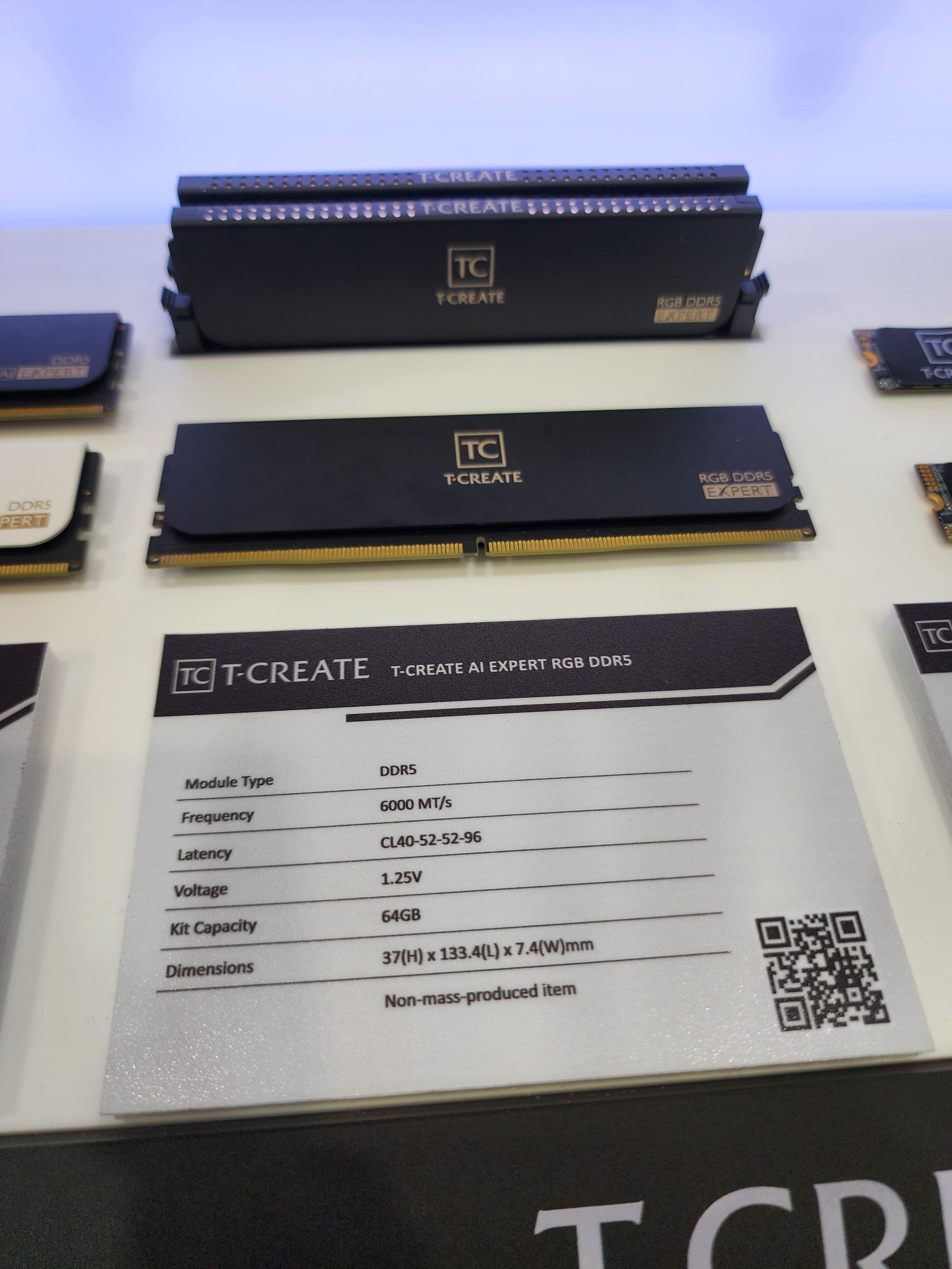 A display of TeamGroup T-CREATE AI Expert RGB DDR5 memory modules alongside a specification sheet showing details like '6000 MT/s' frequency, '64GB' capacity, and '1.25V' voltage.