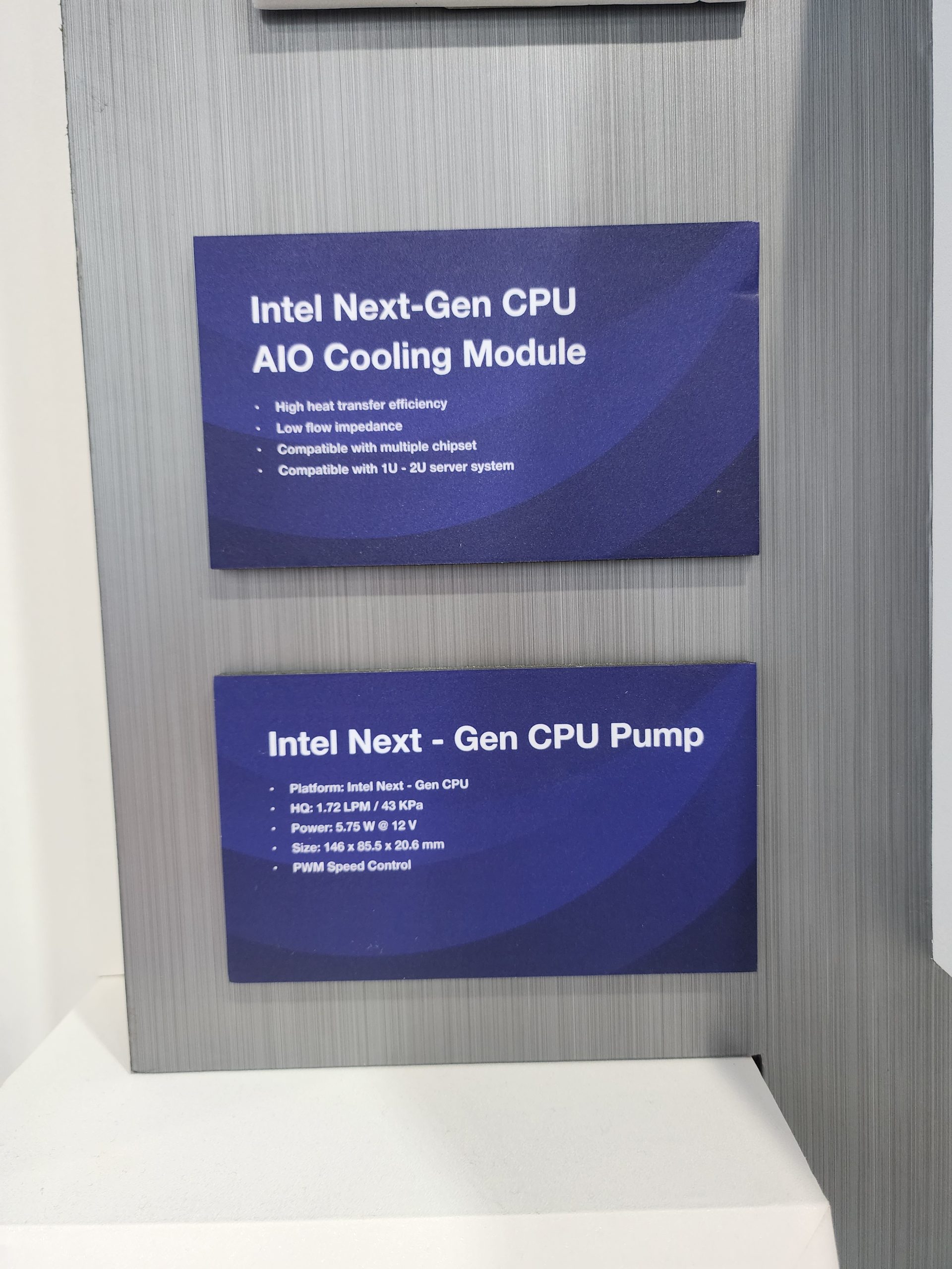 Two signs display the 'Intel Next-Gen CPU AIO Cooling Module' and 'Intel Next-Gen CPU Pump,' detailing features like high heat transfer efficiency and low flow impedance for the cooling module, and 1.72 LPM flow rate with PWM speed control for the pump.