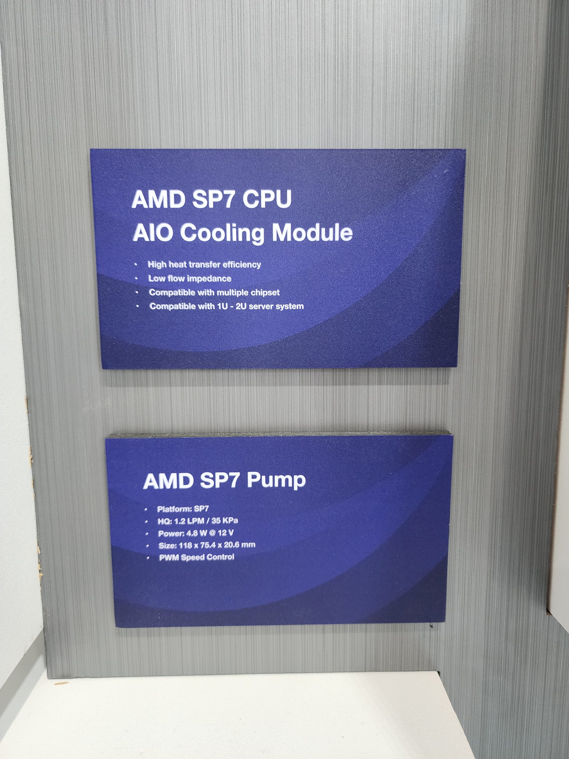 Two informational signs display details about the 'AMD SP7 CPU AIO Cooling Module' highlighting high heat transfer efficiency and compatibility with 1U-2U server systems, and the 'AMD SP7 Pump' noting 12 LPM flow rate and PWM speed control.