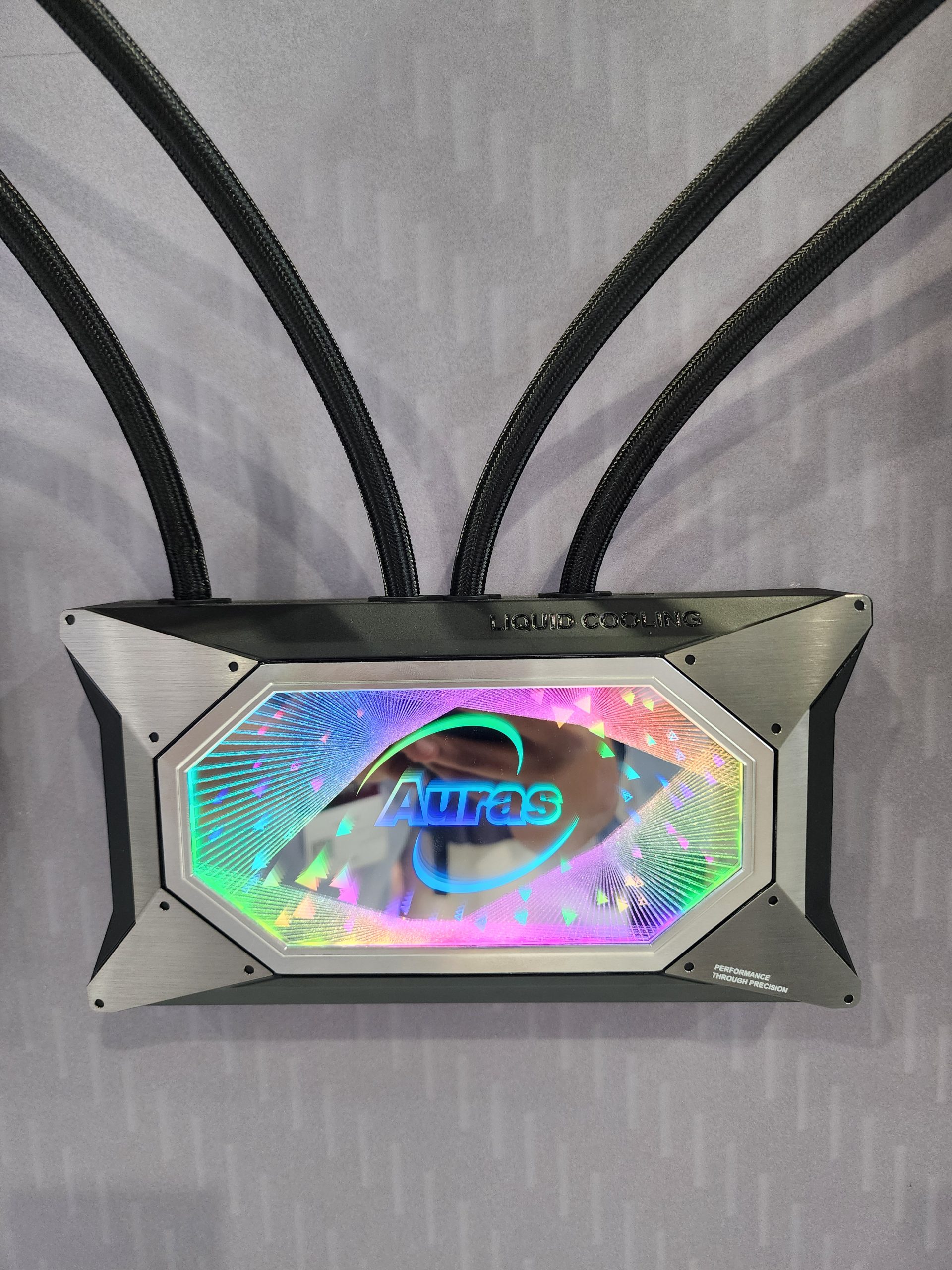 An Auras liquid cooling system with multi-colored LED display and text 'Performance Through Precision' engraved on the casing.