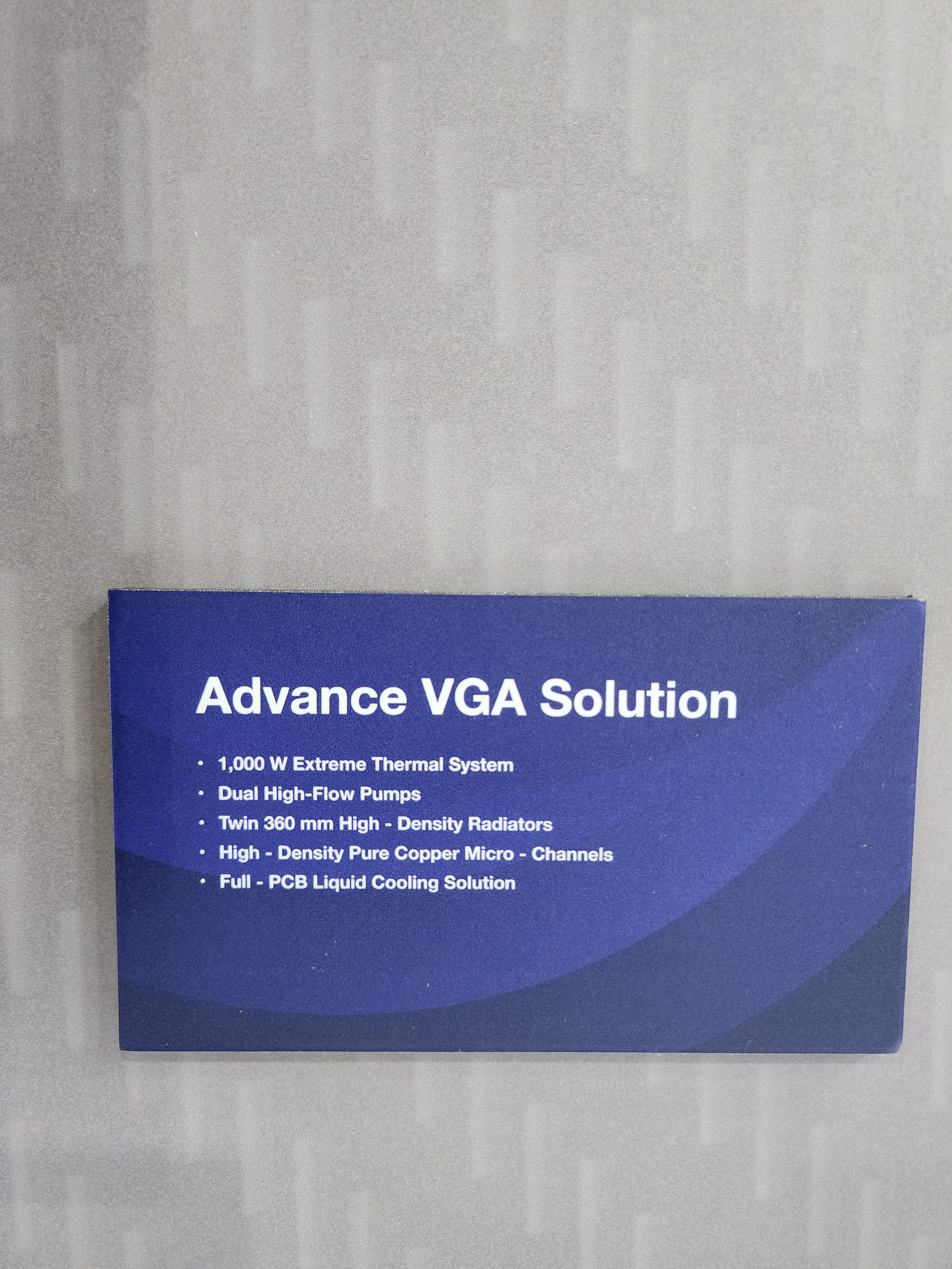 A blue sign titled 'Advance VGA Solution' lists features such as '1,000 W Extreme Thermal System,' 'Dual High-Flow Pumps,' 'Twin 360 mm High-Density Radiators,' 'High-Density Pure Copper Micro-Channels,' and 'Full-PCB Liquid Cooling Solution.'