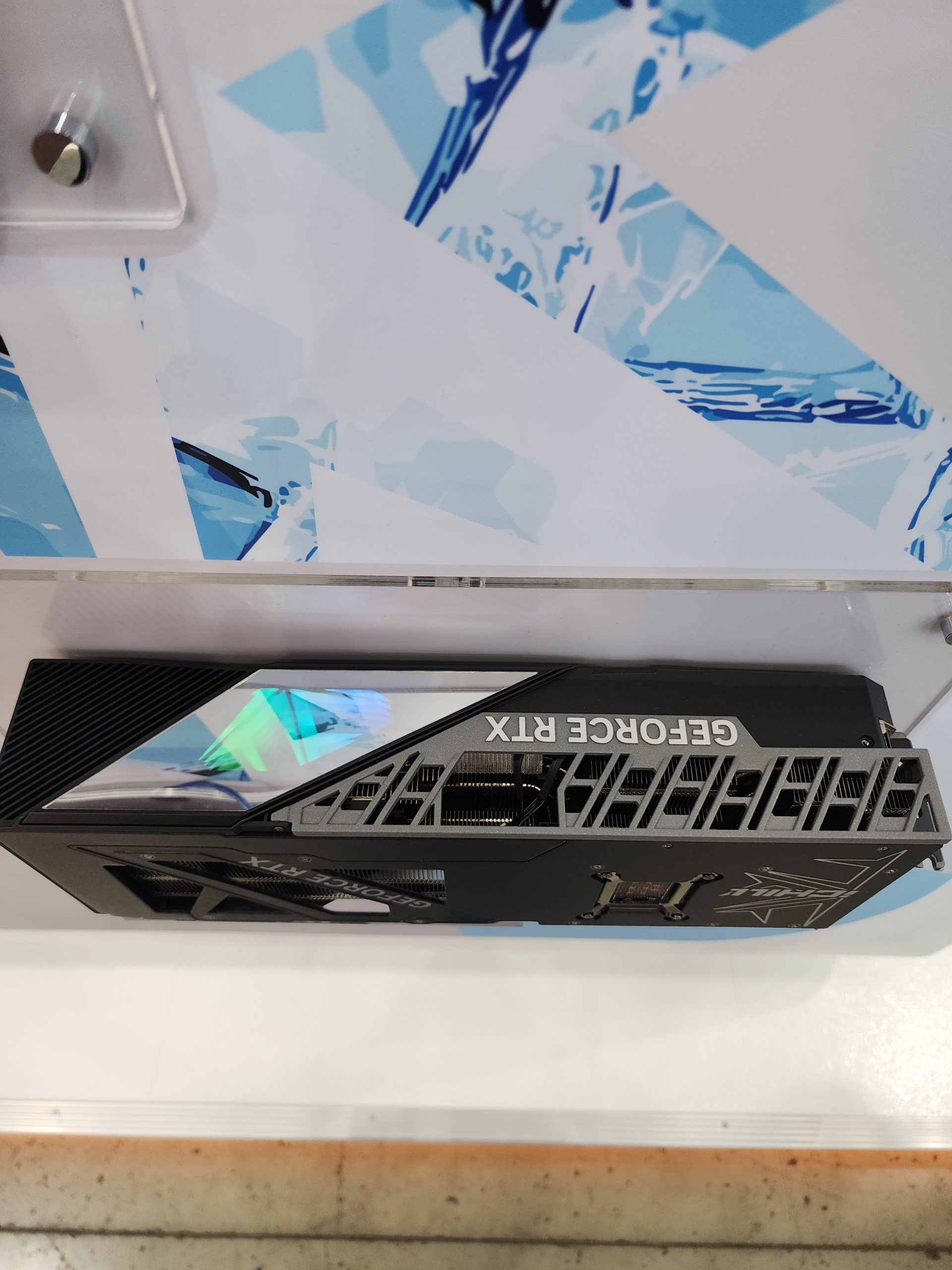 A NVIDIA GeForce RTX graphics card is mounted on a display panel with visible architectural designs in the background.