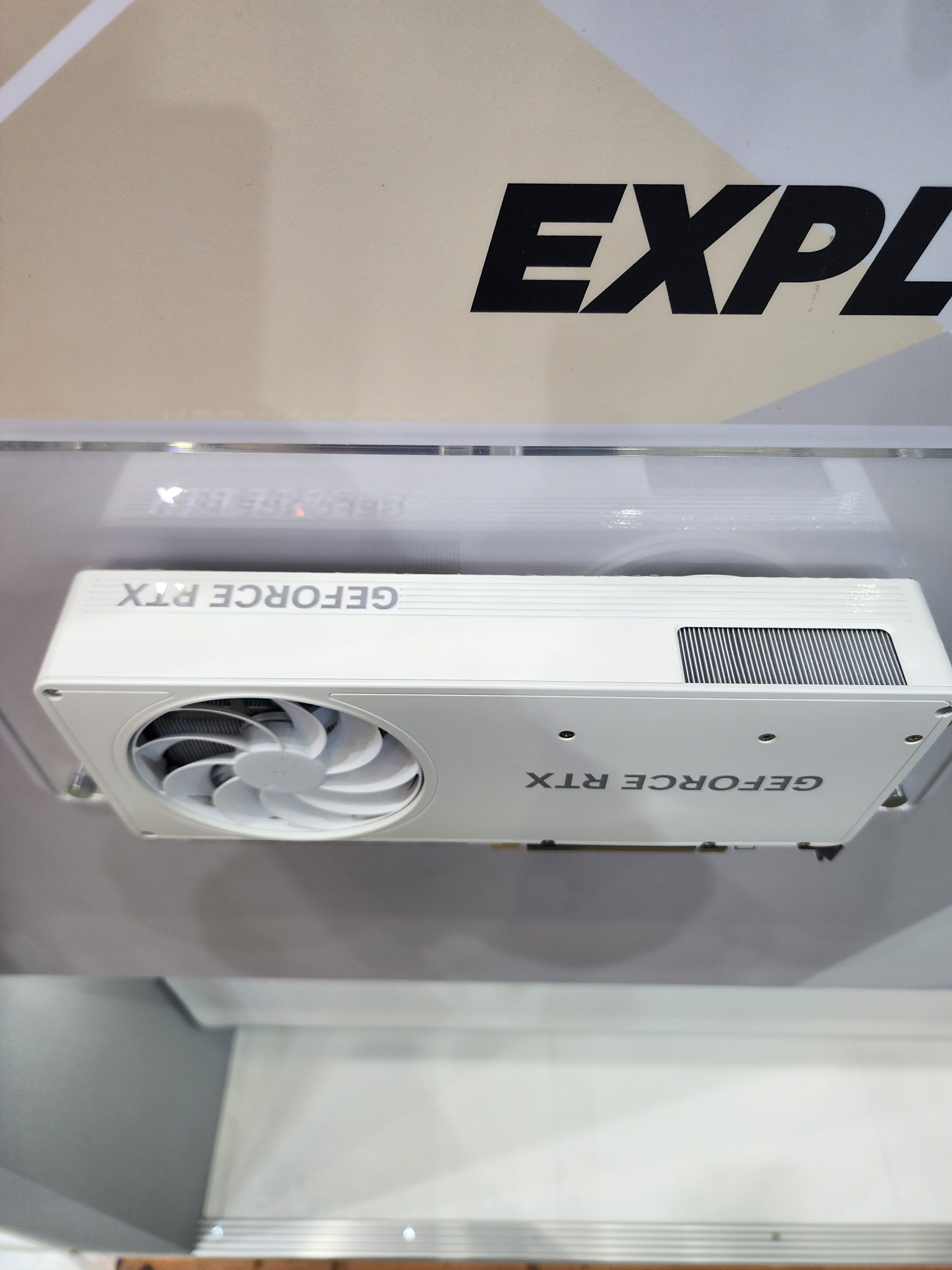 A white 'GEFORCE RTX' graphics card with a single fan is displayed horizontally.