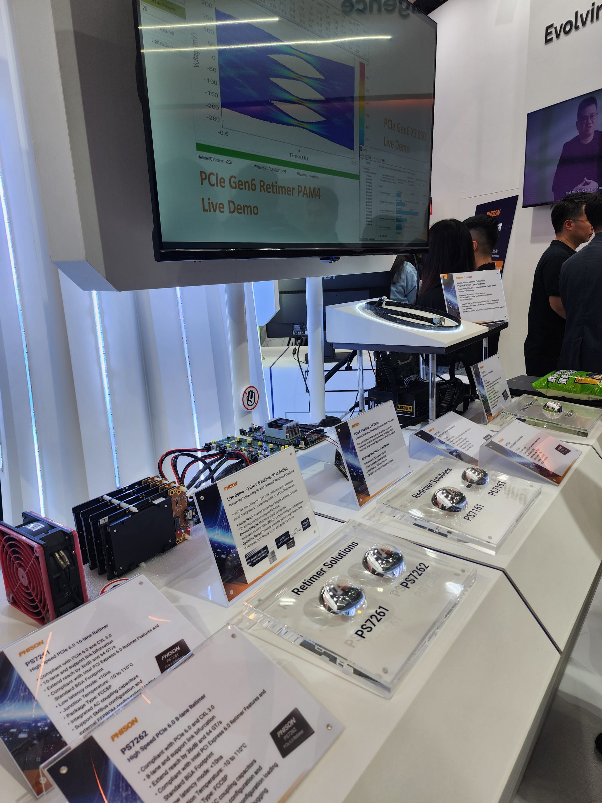 A display featuring Phison PS7261 and PS7262 retimer solutions is showcased with an on-screen demo titled 'PCIe Gen6 Retimer PAM4 Live Demo' at an exhibit booth.