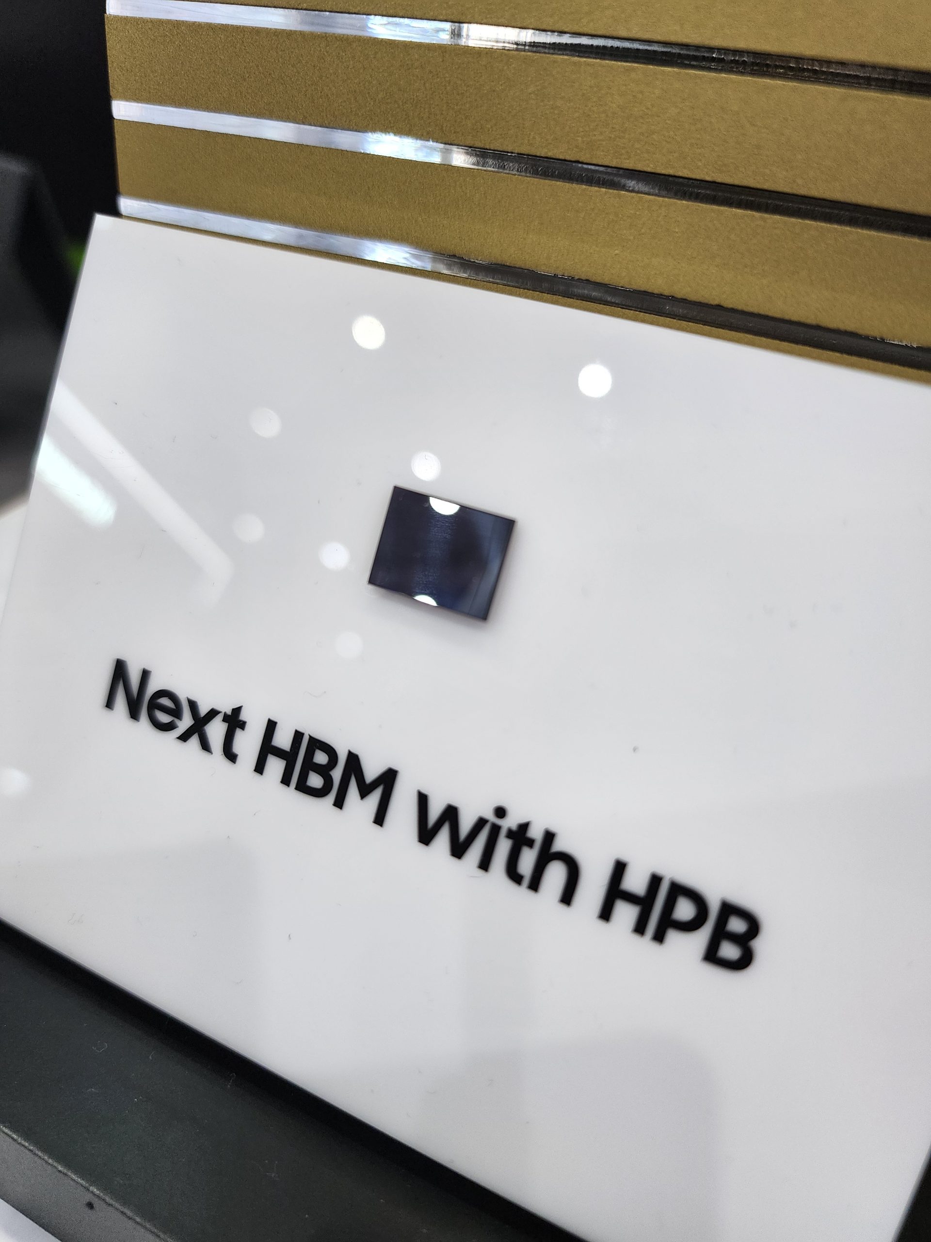 A small chip is displayed with the text 'Next HBM with HPB' underneath it on a white platform.