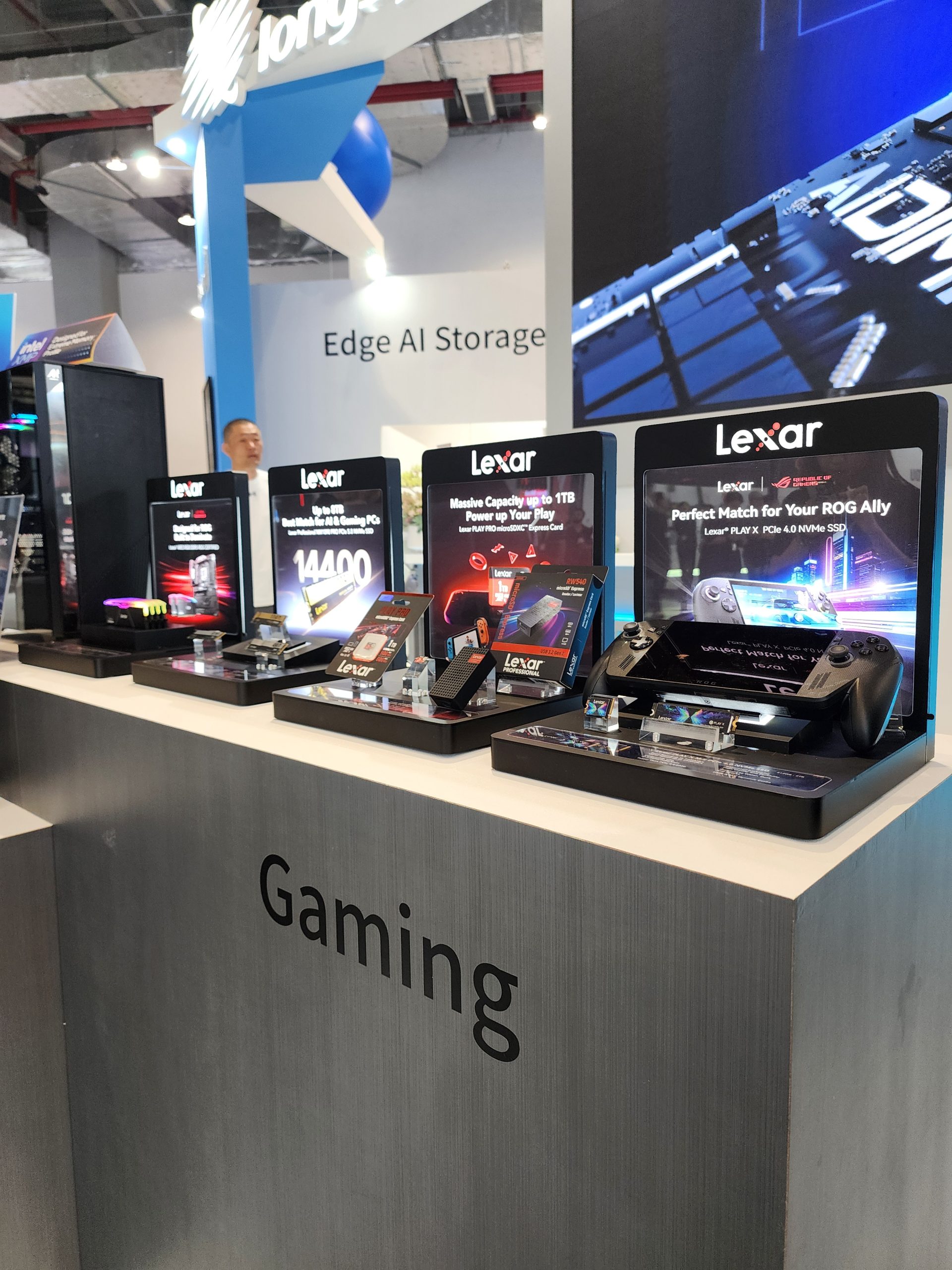 A display of Lexar storage products including 'Massive Capacity up to 1TB' and 'Perfect Match for your ROG Ally' at a tech expo, with a focus on gaming.