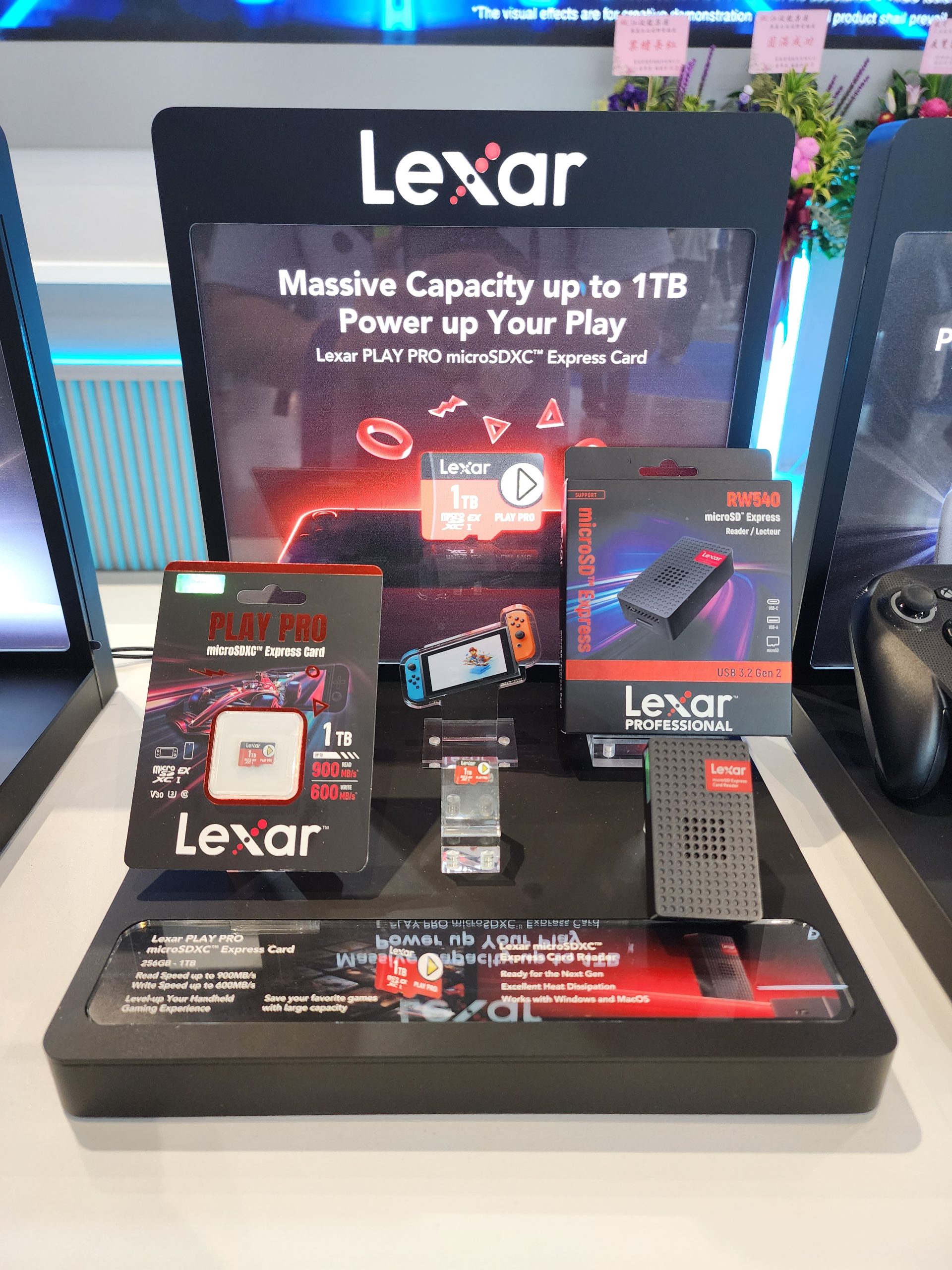 A display of Lexar products showcases the Lexar PLAY PRO microSDXC Express Card with 'Massive Capacity up to 1TB,' alongside an SSD marked Lexar Professional RWS540 and package showing '1TB,' '900MB/s read,' and '600MB/s write.'