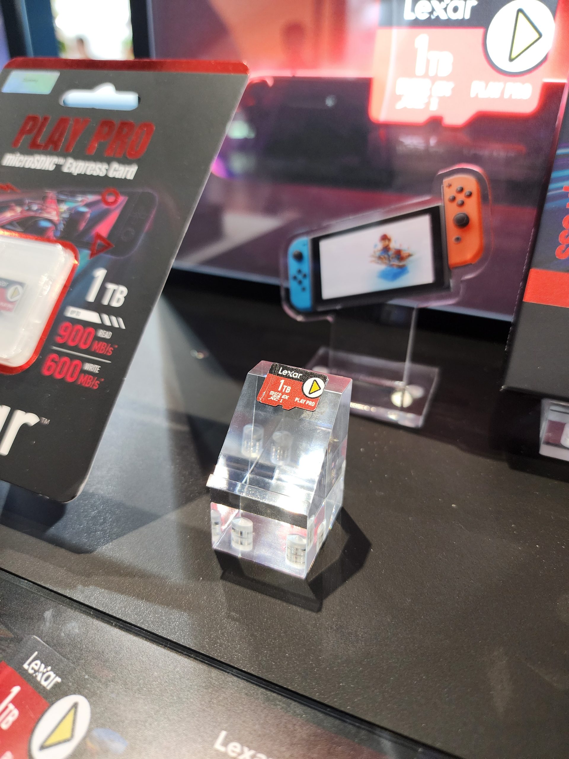 A Lexar Play Pro microSDXC Express Card with '1TB' capacity and '900 MB/s' read speed is displayed next to a Nintendo Switch model.