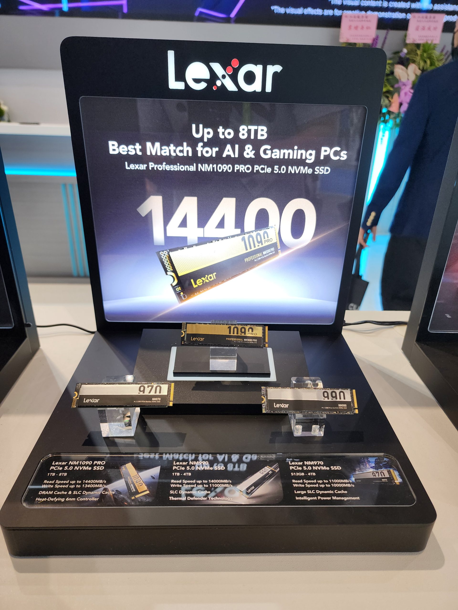A display showcases the Lexar Professional NM1090 PRO PCIe 5.0 NVMe SSD with a read speed of up to 14400MB/s and up to 8TB capacity, suitable for AI and gaming PCs.