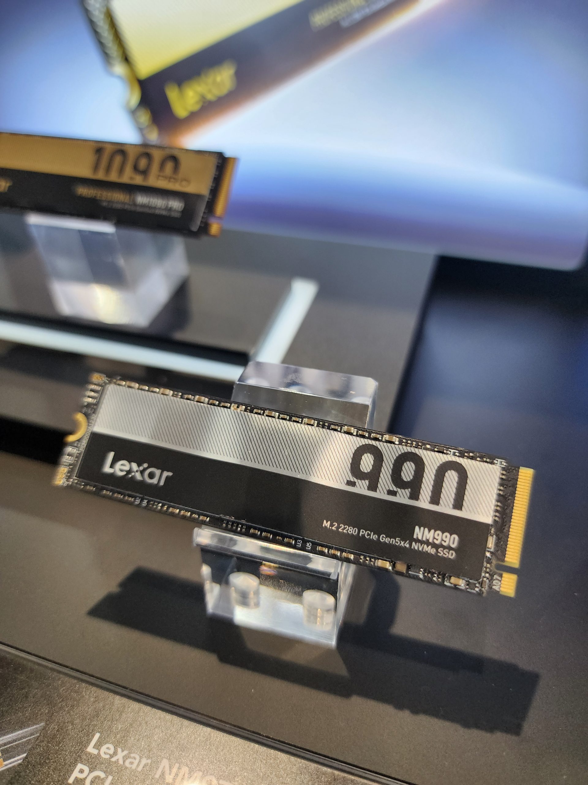 A Lexar NM990 M.2 2280 PCIe Gen5x4 NVMe SSD is displayed on a stand, with its branding clearly visible.