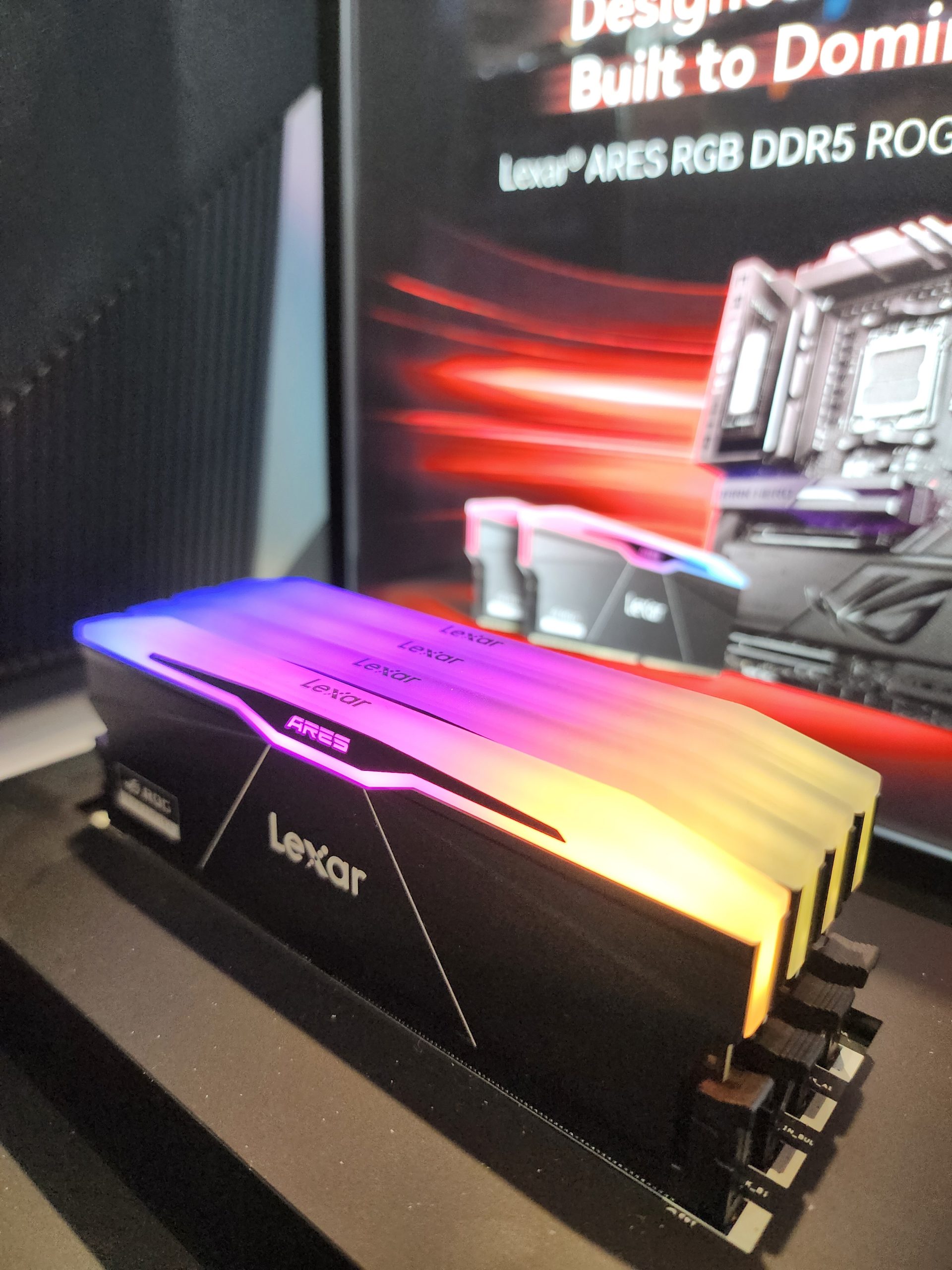 Lexar ARES RGB DDR5 RAM modules with colorful lighting are displayed on a black surface, with promotional text in the background.