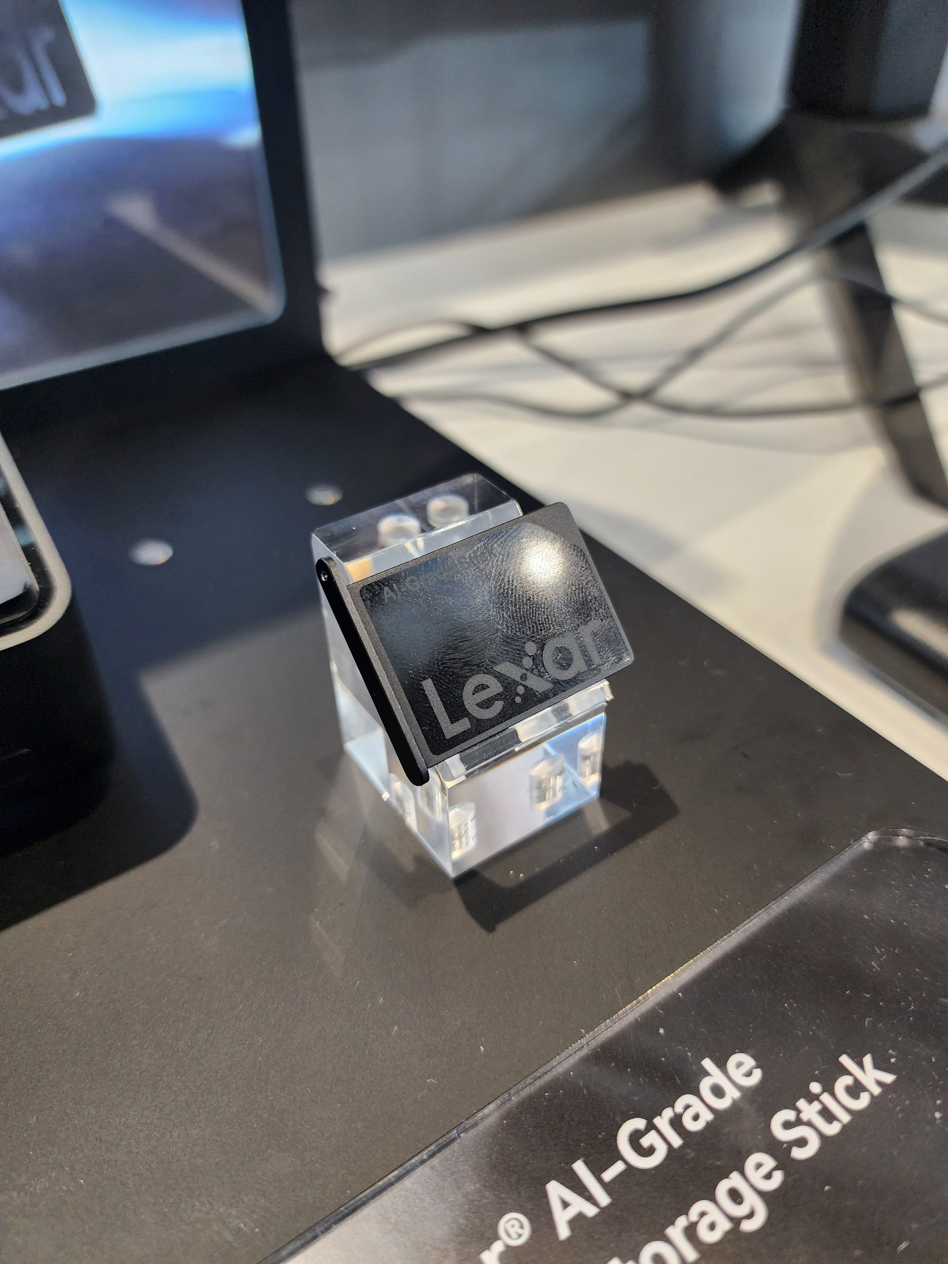A Lexar portable storage drive is displayed on a black stand labeled Lexar AI-Grade Storage Stick.