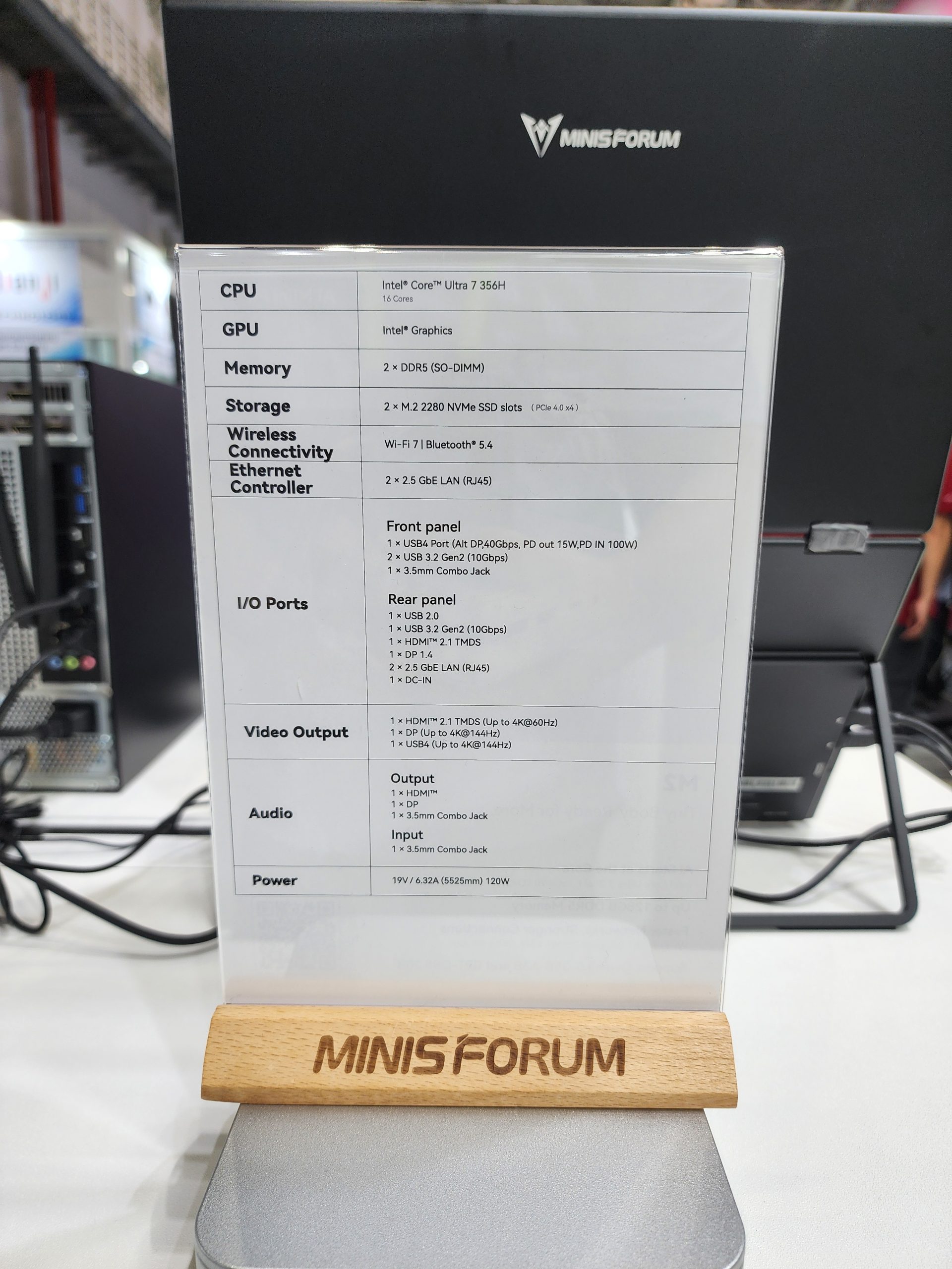 A MINISFORUM display shows specifications for a device with an Intel Core Ultra 7 356H CPU, Intel Graphics, 2 × DDR5 memory slots, Wi-Fi 7, Bluetooth 5.4, and multiple connectivity ports including USB, HDMI, and DP.