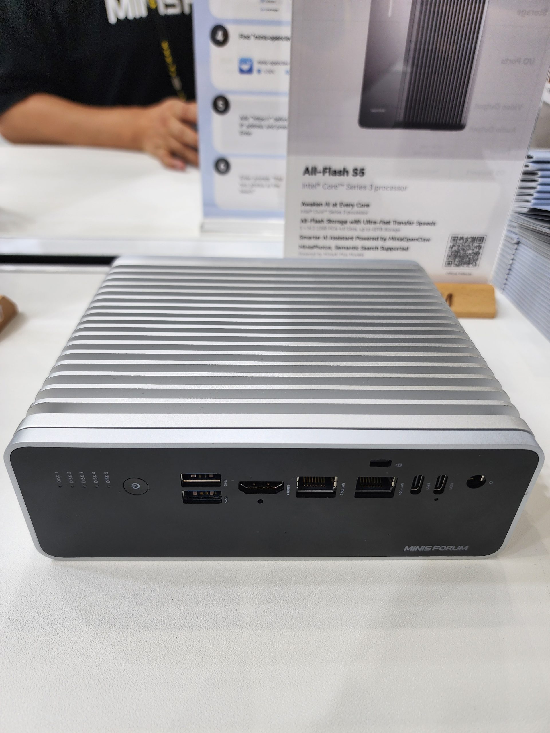 The MinisForum All-Flash S5 with multiple ports and 'Intel Core' Series 3 processor text is displayed next to an information stand.