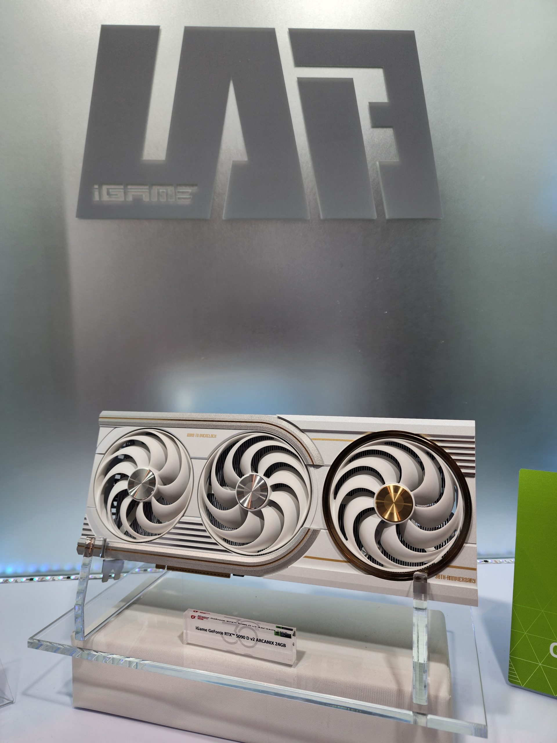 A Colorful iGame GeForce RTX 5090 Vulcan Next graphics card with three fans is displayed on a stand.