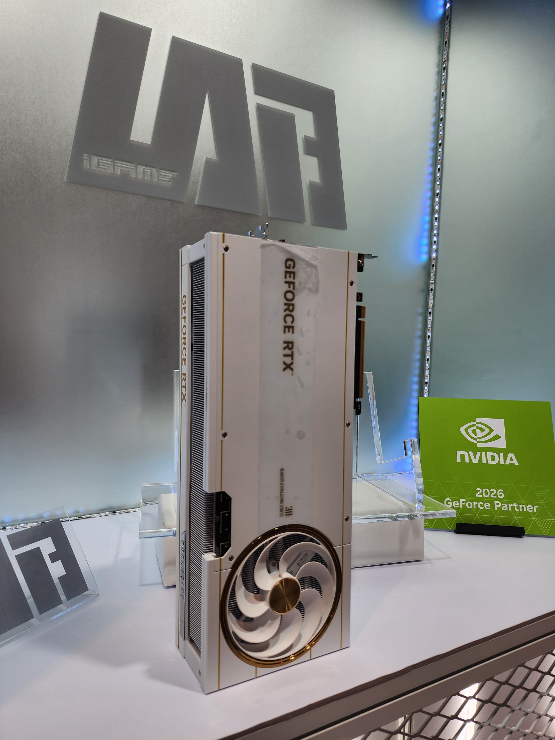 A Colorful iGame GeForce RTX graphics card is displayed vertically next to a sign reading 'NVIDIA 2026 GeForce Partner.'