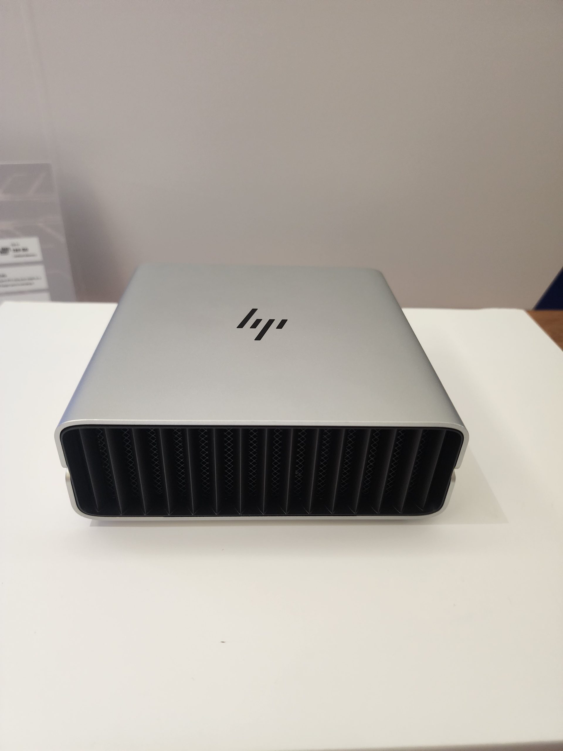 A silver HP desktop mini PC with a front vent design, featuring the HP logo on top.
