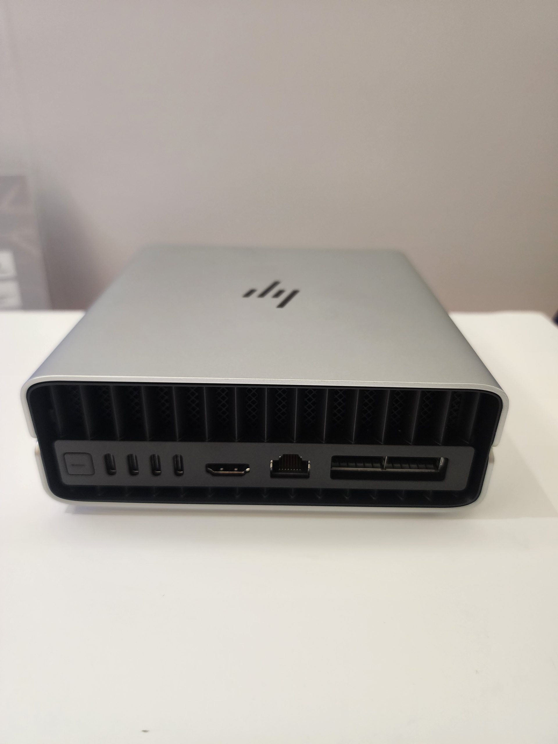 A silver HP external docking station showing rear ports including USB-C, HDMI, Ethernet, and power button.