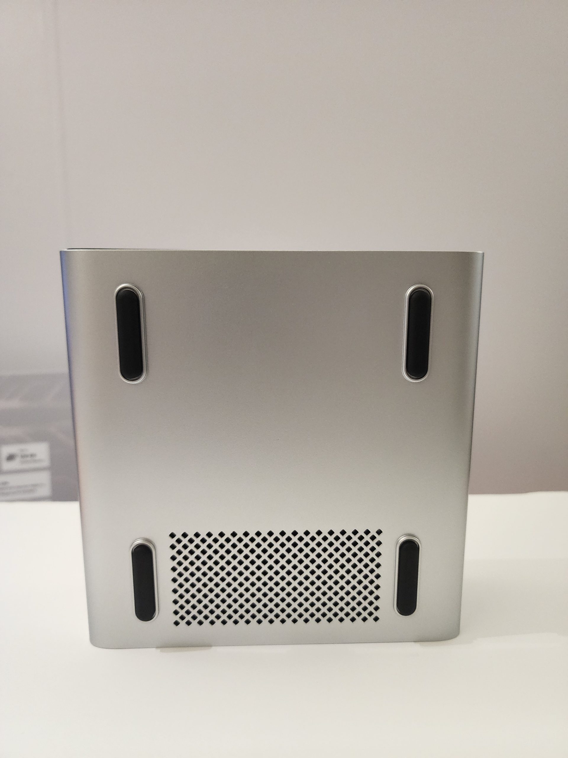 The bottom view of a silver, unbranded PC case, featuring four black rubber feet and a vented mesh panel for airflow.
