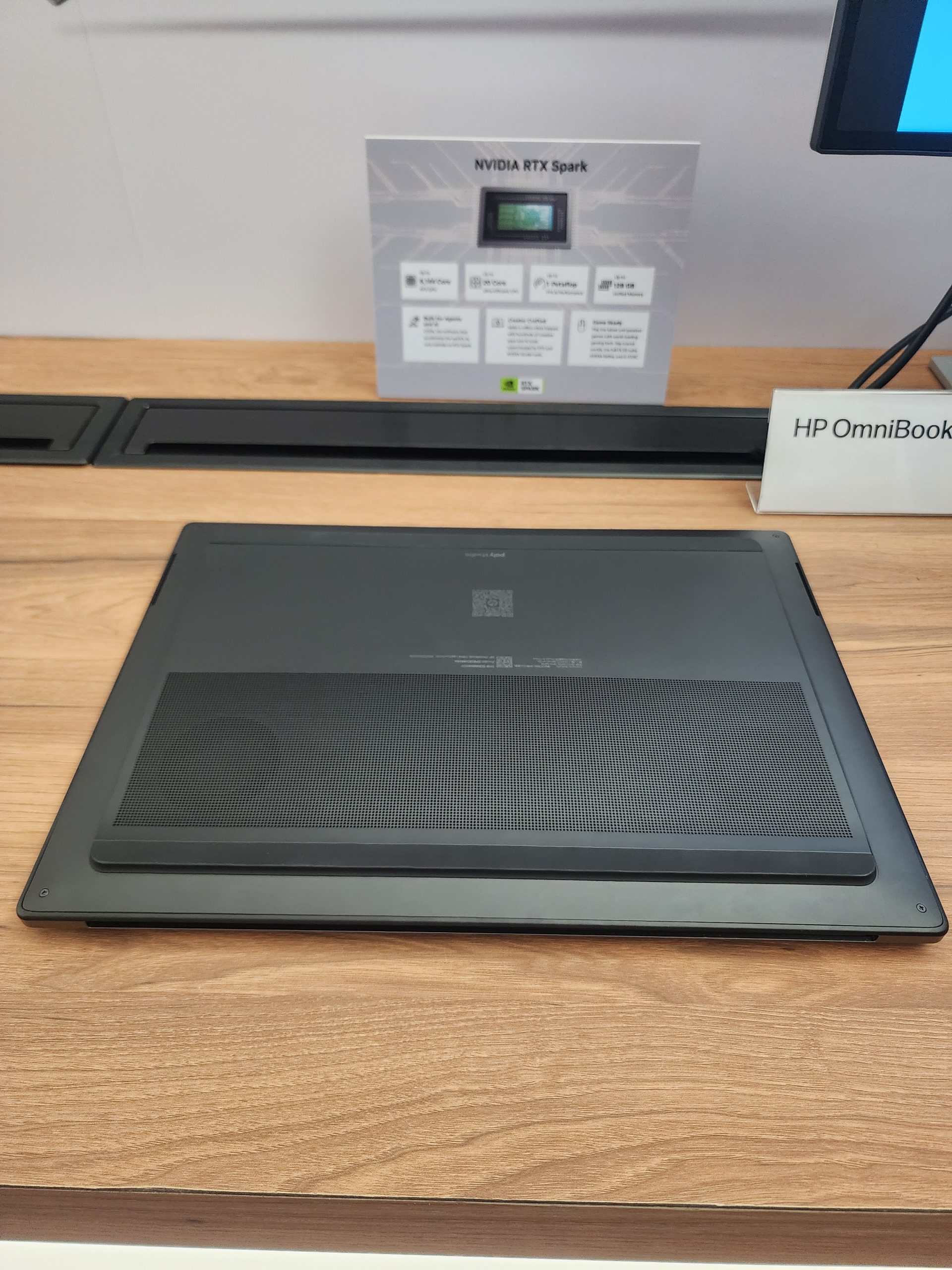 An HP OmniBook laptop is displayed on a table, with a sign in the background titled 'NVIDIA RTX Spark.'