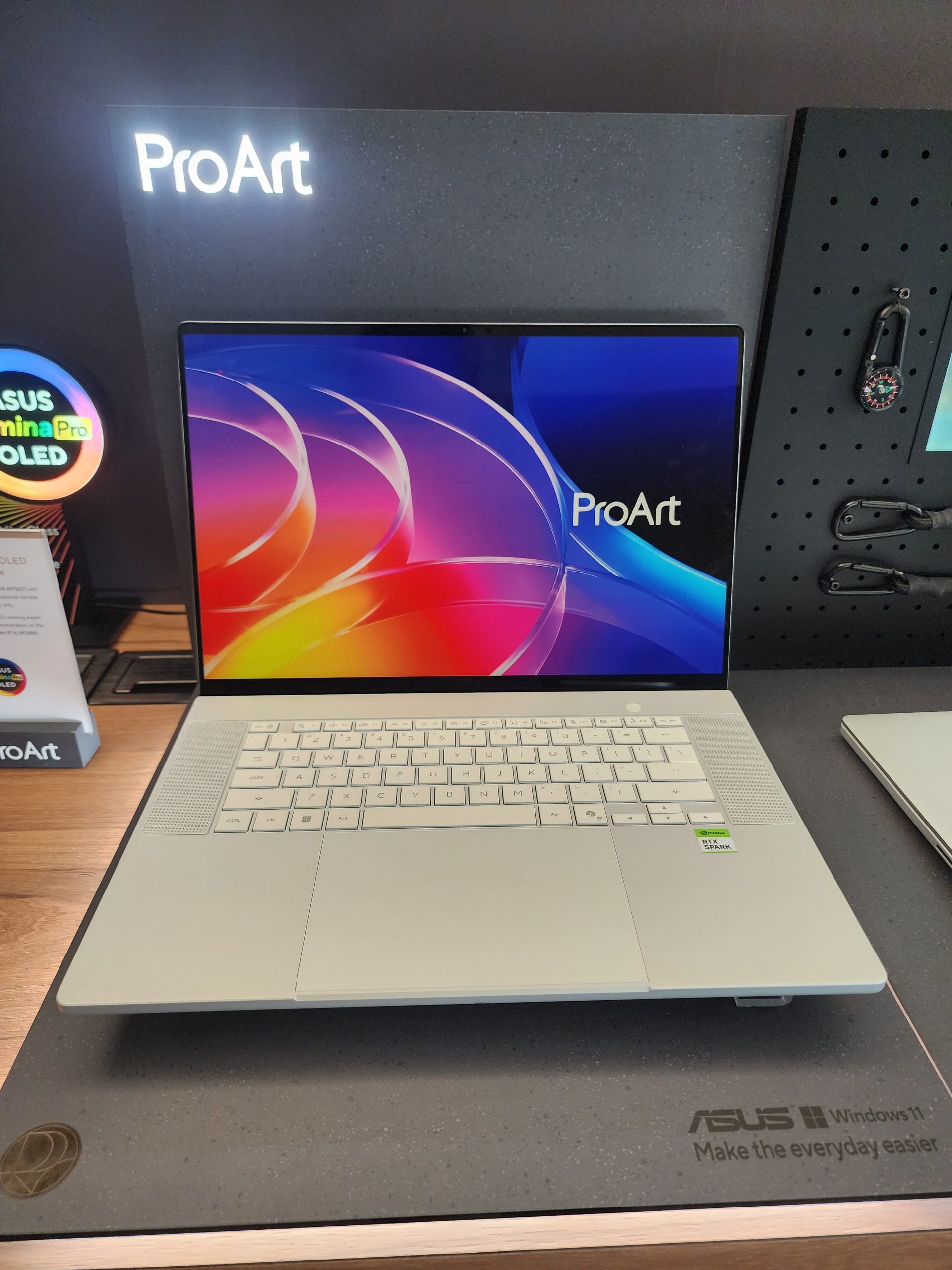 An ASUS ProArt laptop with a colorful display sits on a desk featuring branding and 'NVIDIA Studio' and 'Intel Core' labels, alongside the text 'ASUS Windows 11 Make the everyday easier' at the corner.