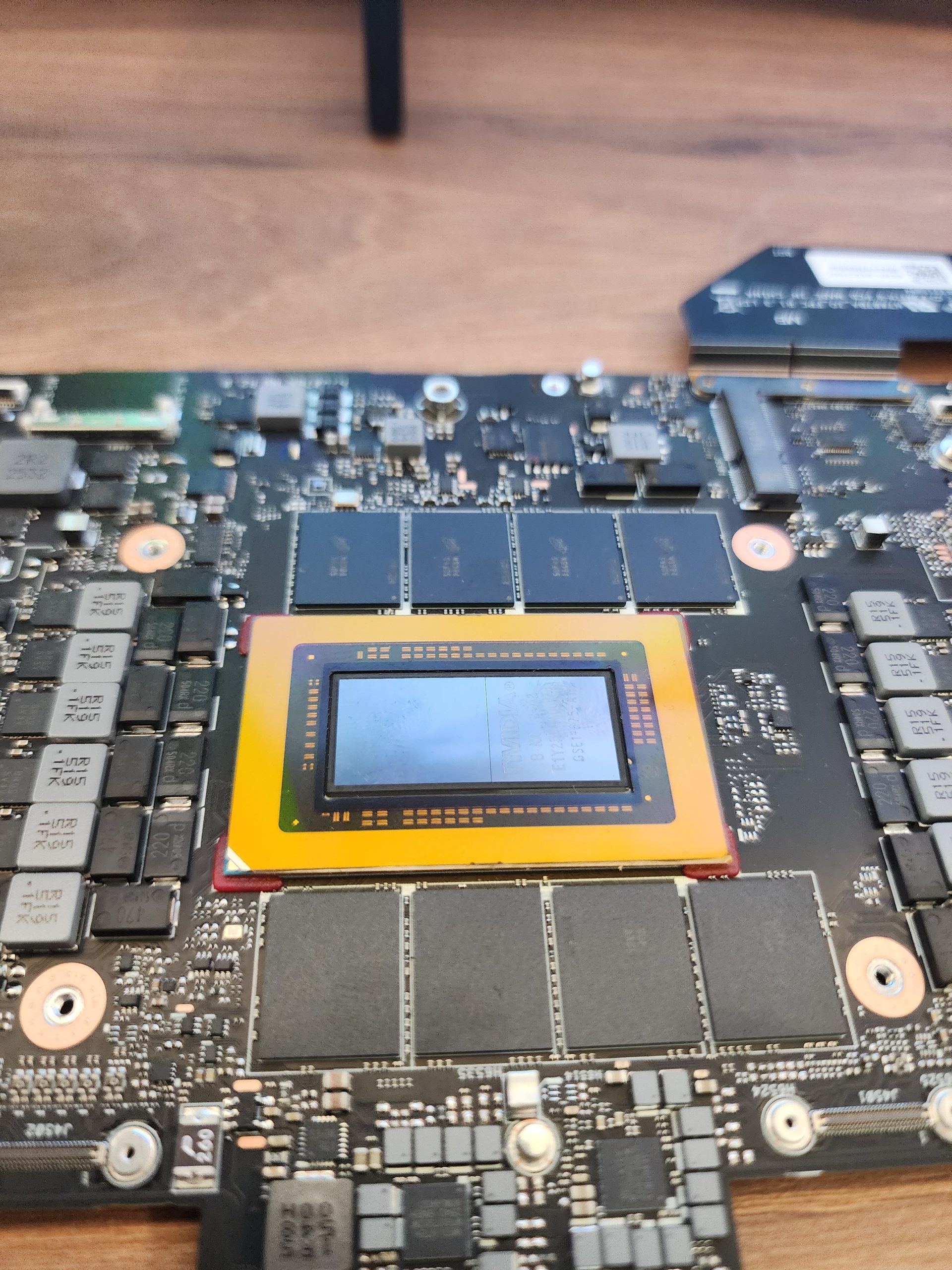 A close-up of an NVIDIA graphics card showing the GPU chip surrounded by memory modules on a motherboard.