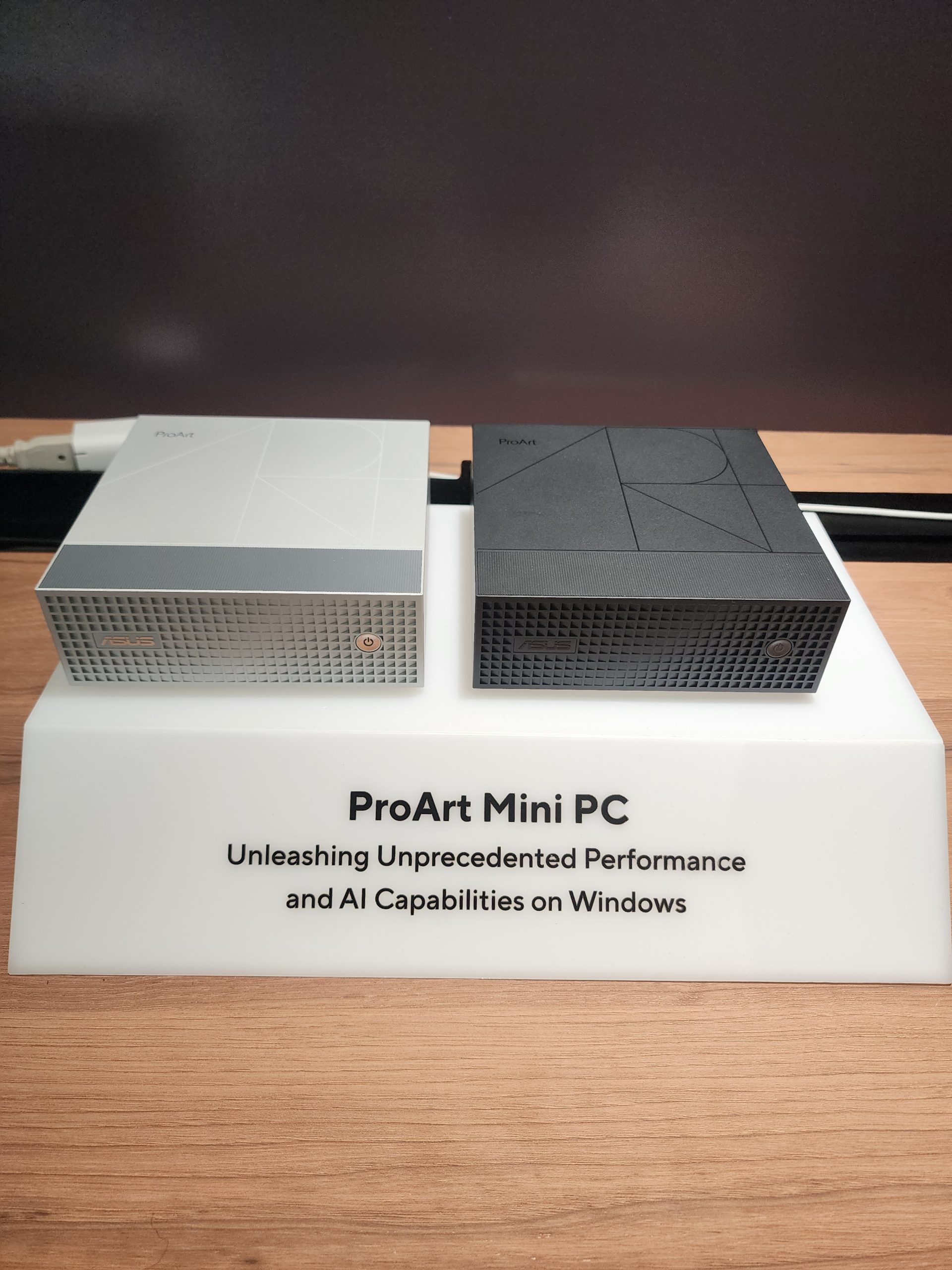 Two ASUS ProArt Mini PCs, in silver and black, are displayed on a stand labeled 'ProArt Mini PC Unleashing Unprecedented Performance and AI Capabilities on Windows.'
