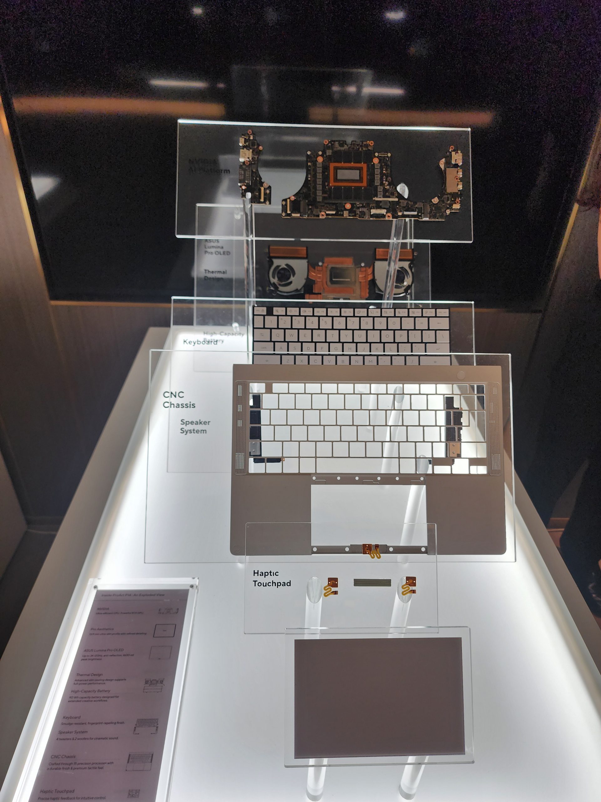A display showing an unbranded laptop's internal components including a motherboard, 'NVIDIA AI Platform,' keyboard, 'CNC Chassis Speaker System,' and 'Haptic Touchpad.'